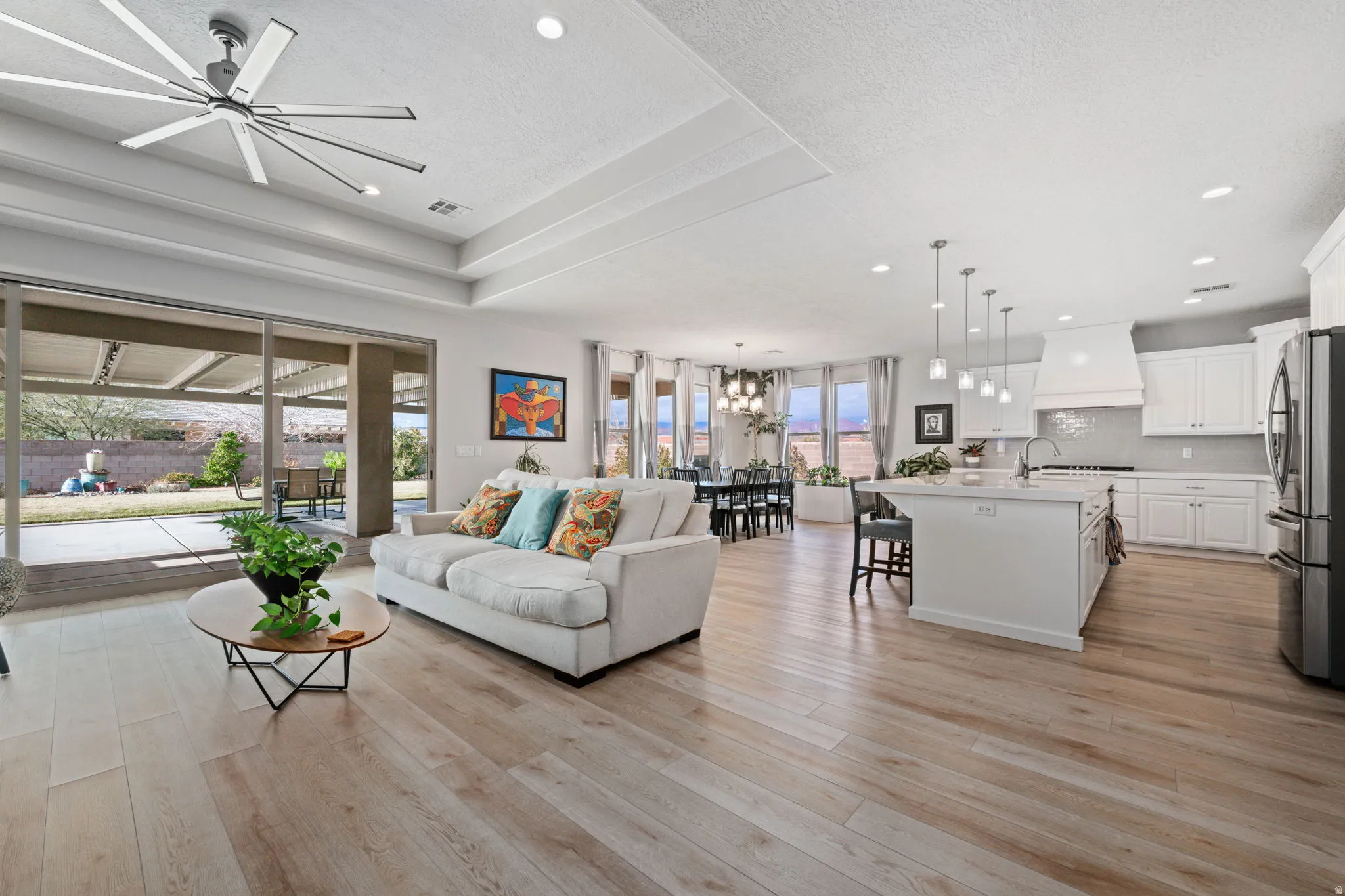 Living area with a textured ceiling, light wood finished floors, a ceiling fan, a chandelier, and recessed lighting