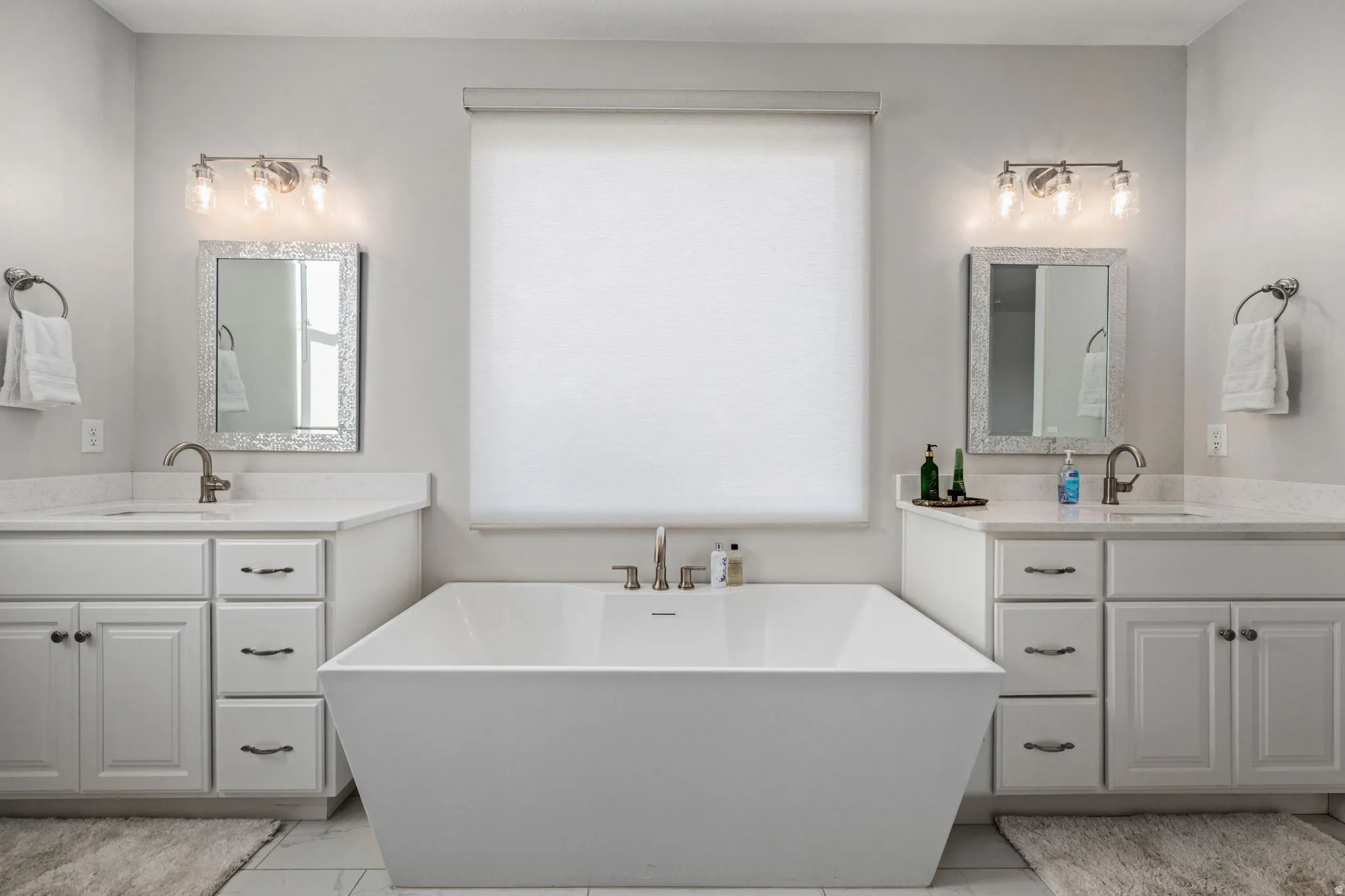 Full bath featuring two vanities, plenty of natural light, and a freestanding bath