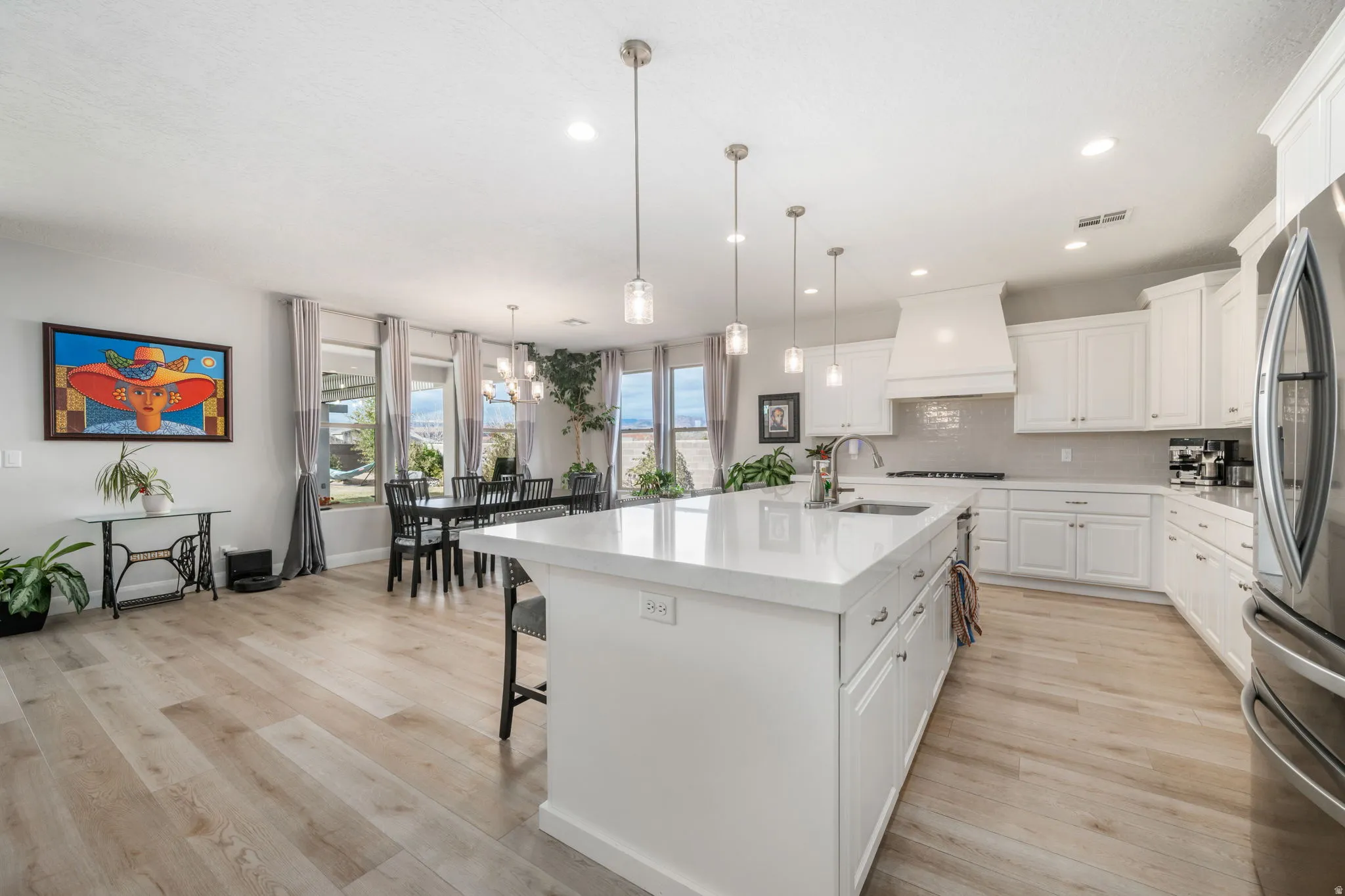 Kitchen with white cabinetry, light wood finished floors, a kitchen island with sink, and recessed lighting