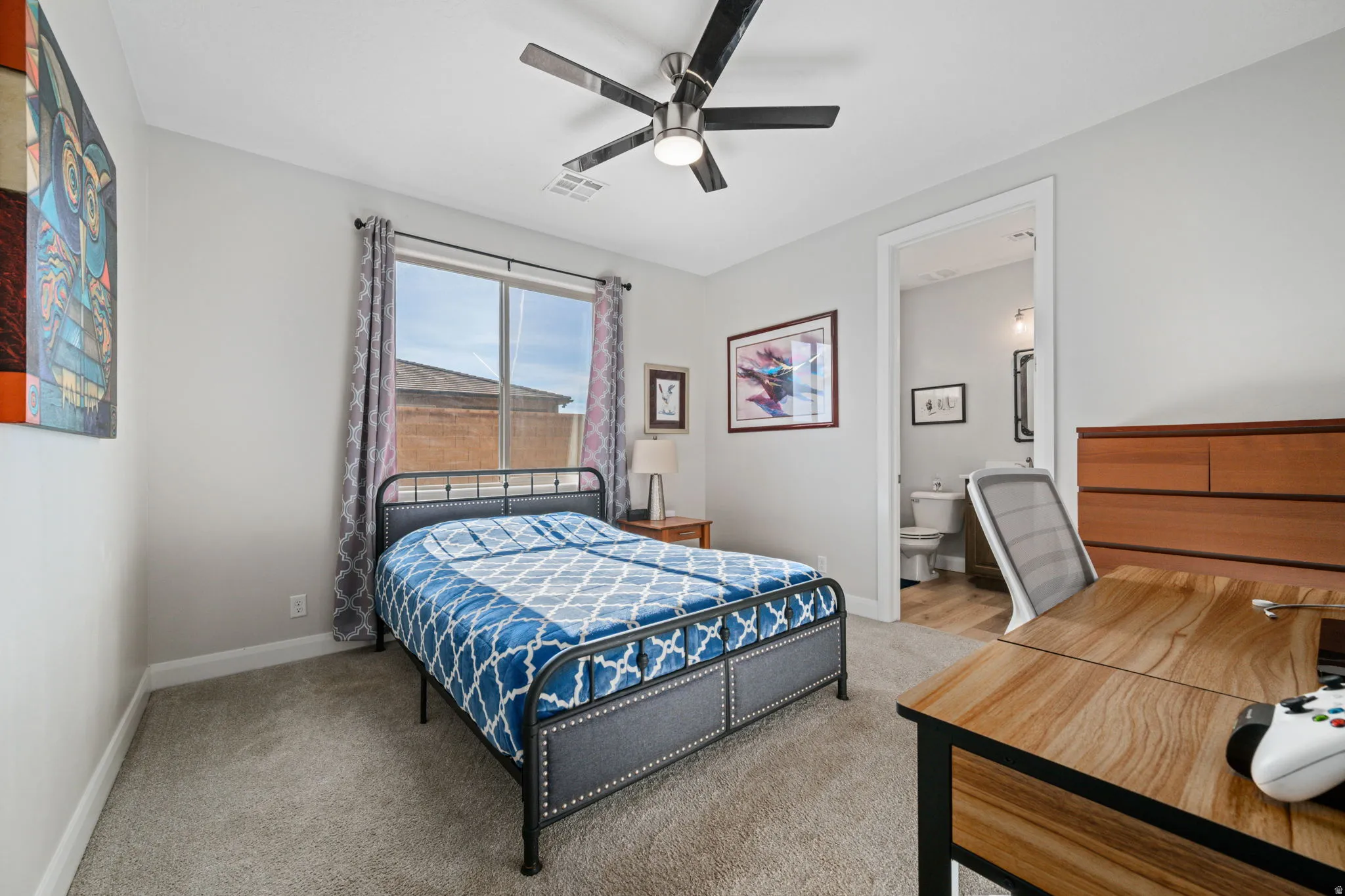 Carpeted bedroom featuring ceiling fan and ensuite bath