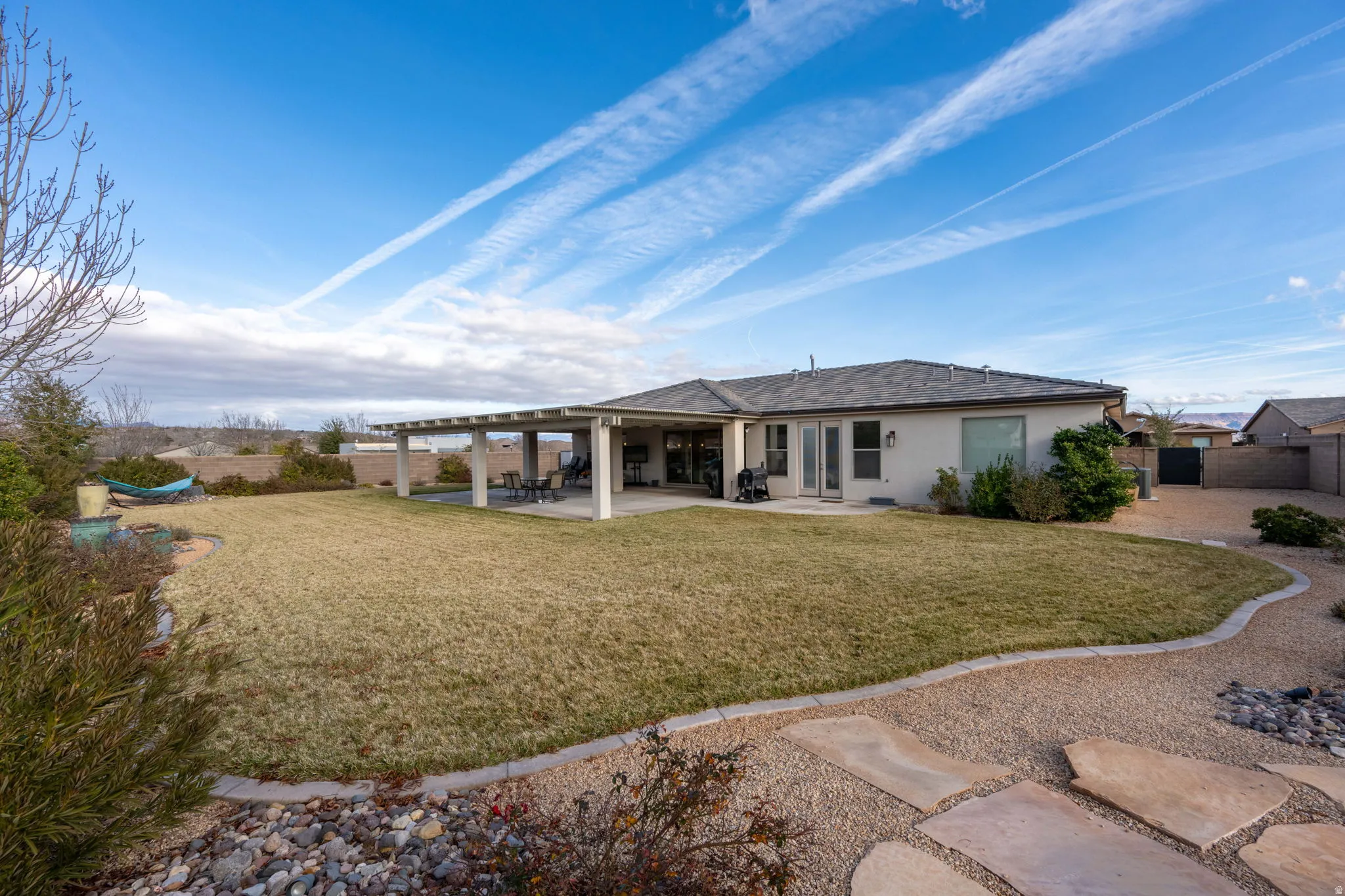 Rear view of property featuring a patio area, stucco siding, and a fenced backyard