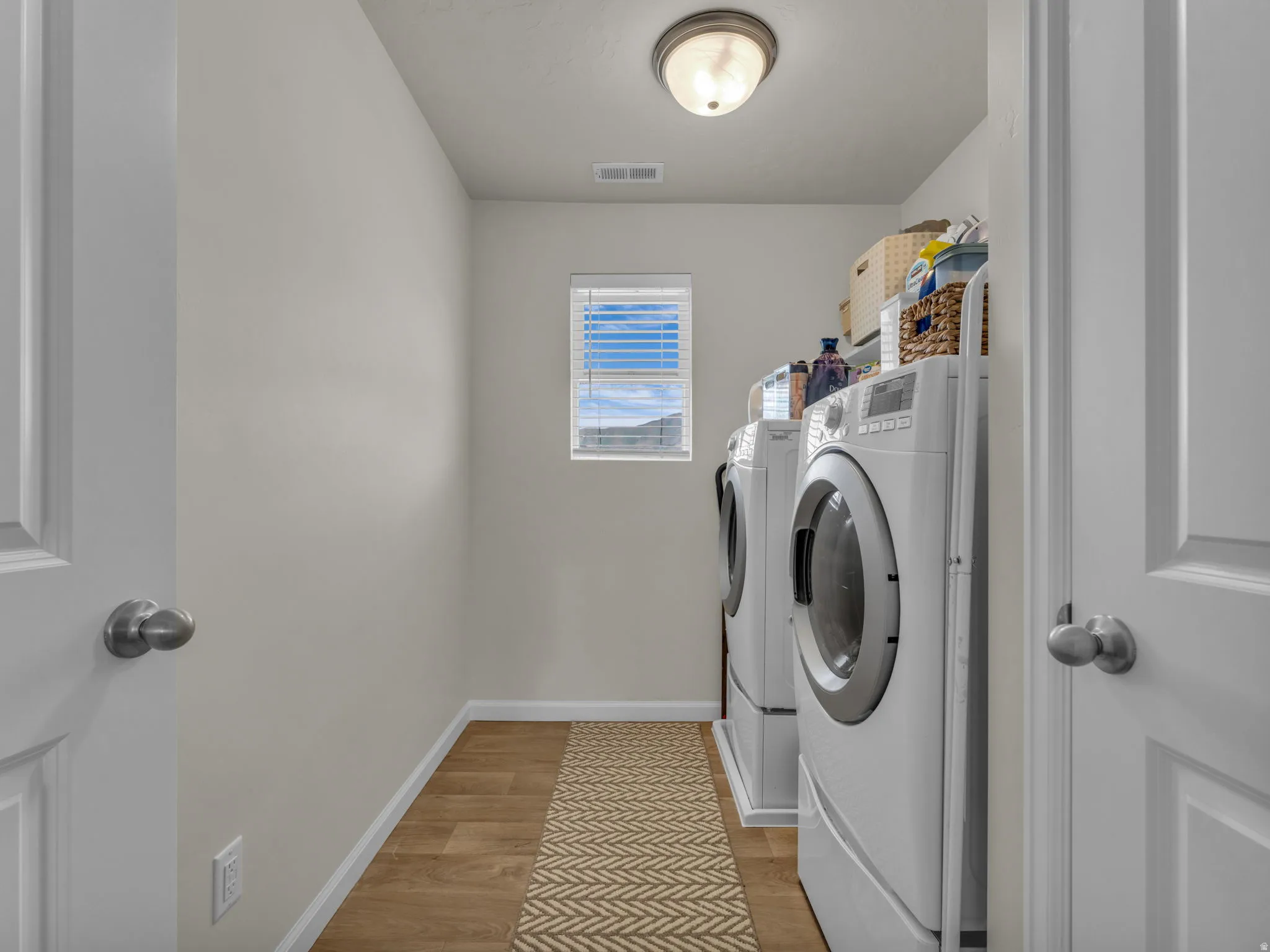 Laundry room with light wood-style floors and washing machine and dryer