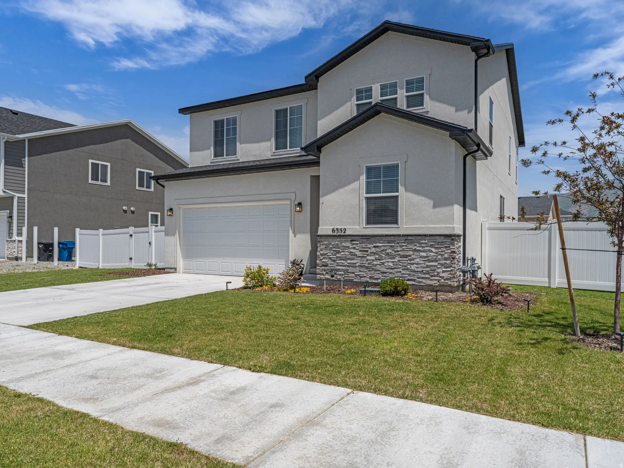 Traditional-style house with stucco siding, stone siding, driveway, and an attached garage