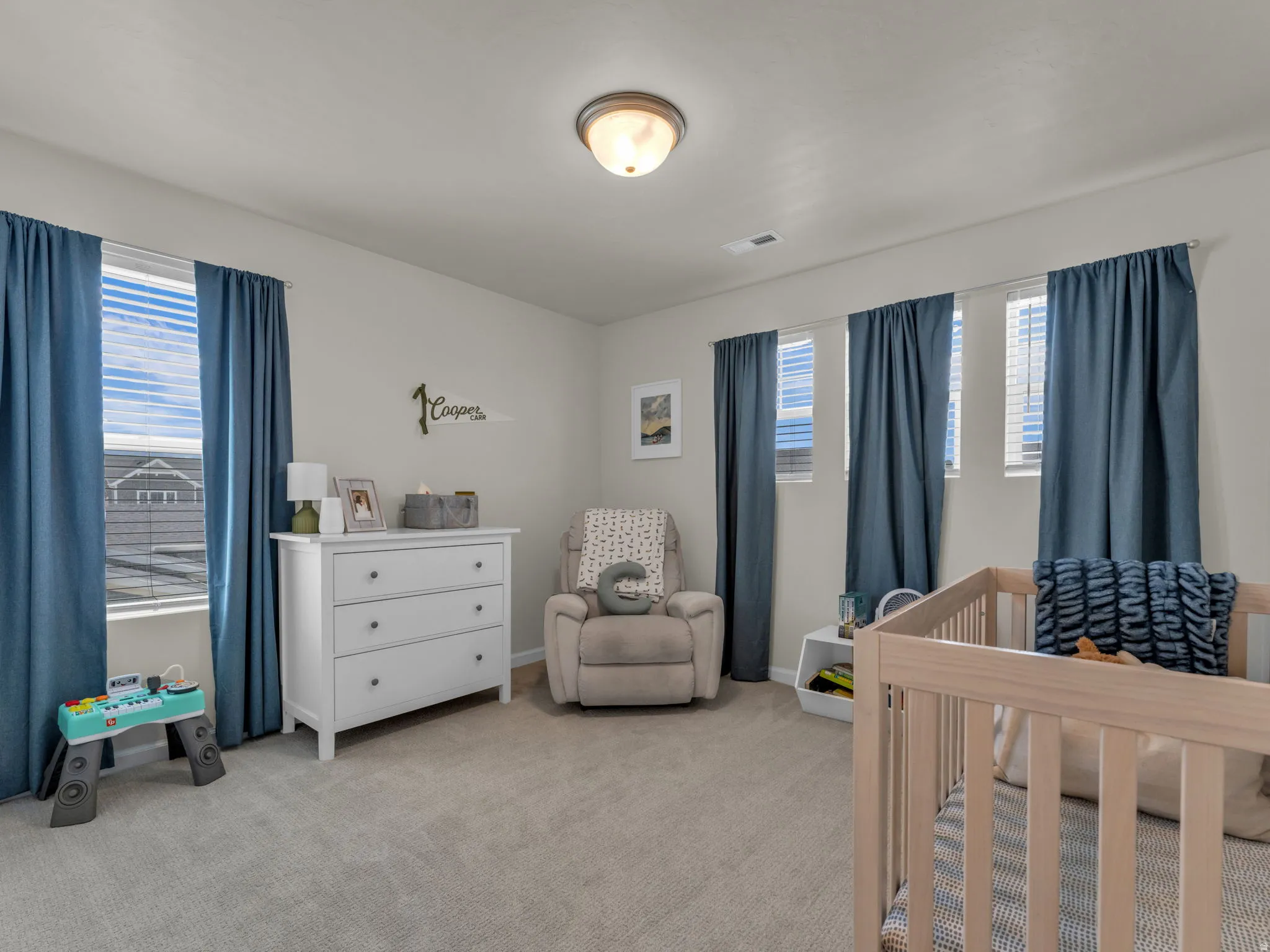 Bedroom with light carpet, a crib, and multiple windows