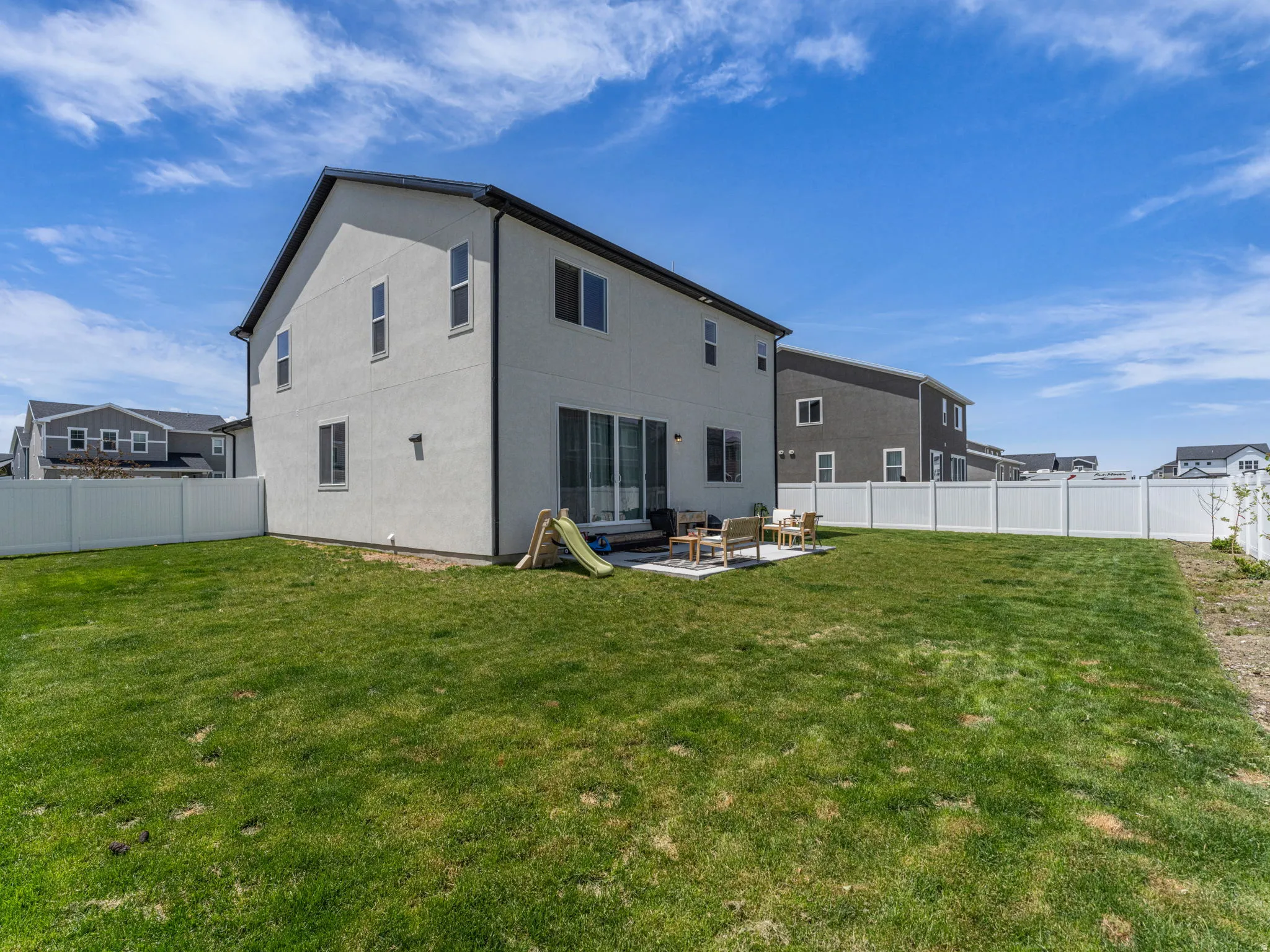 Rear view of house featuring a patio area, a fenced backyard, and stucco siding