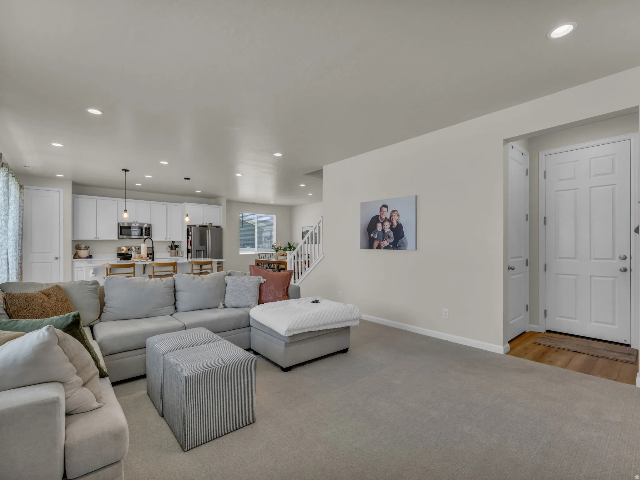 Living area featuring recessed lighting, light colored carpet, and stairs