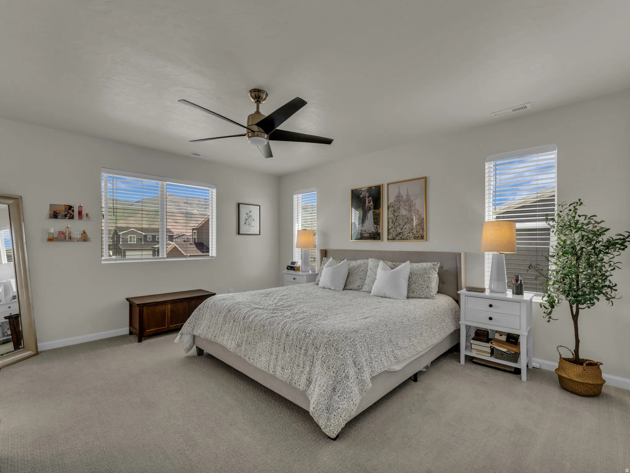 Bedroom with light carpet, multiple windows, and a ceiling fan