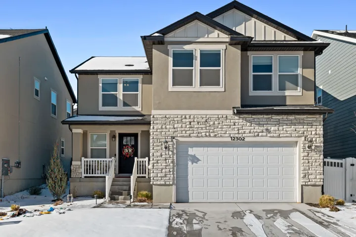 View of front of house with stone siding, a porch, stucco siding, board and batten siding, and a garage