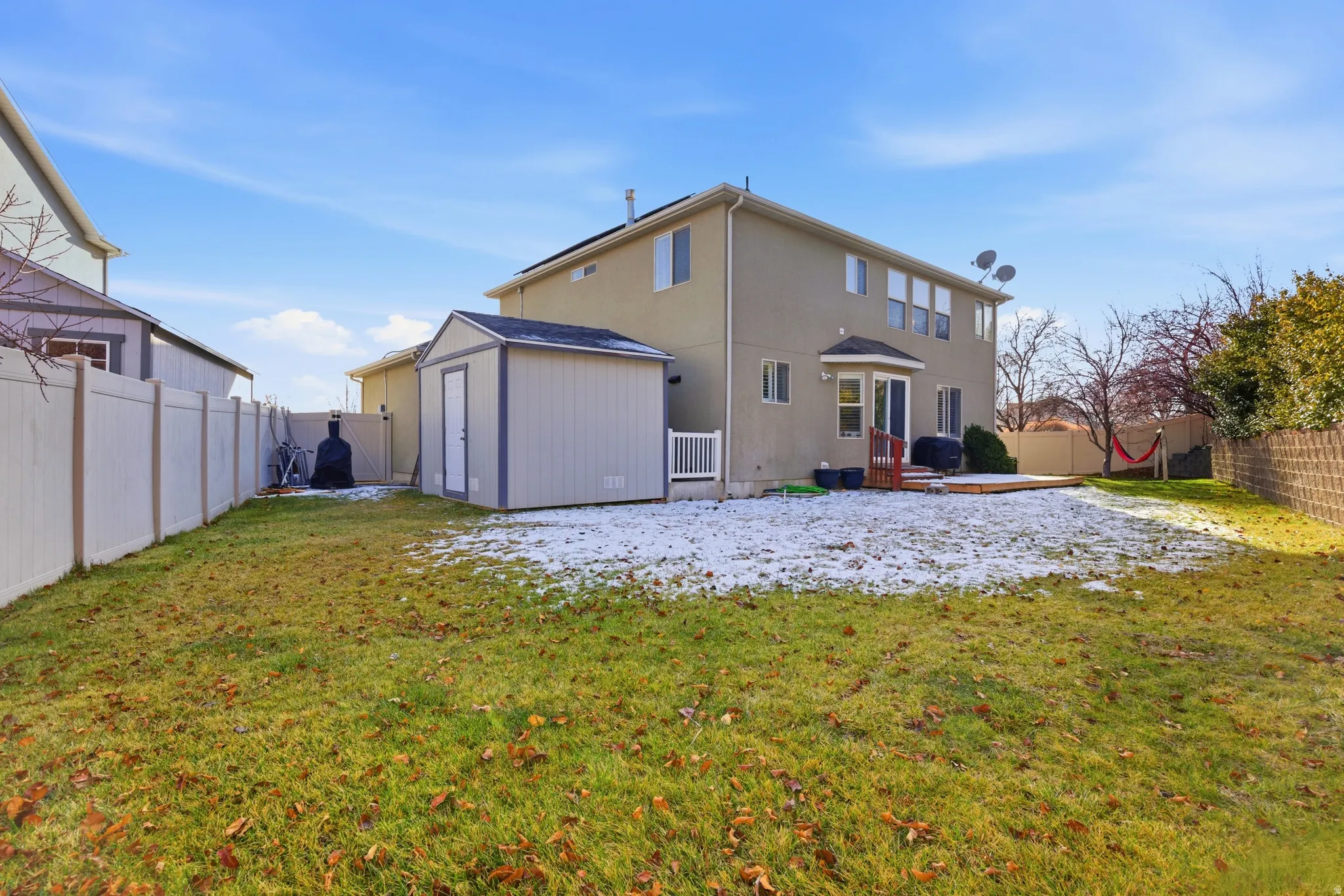 Rear view of house featuring a fenced backyard, a storage unit, a patio, and stucco siding