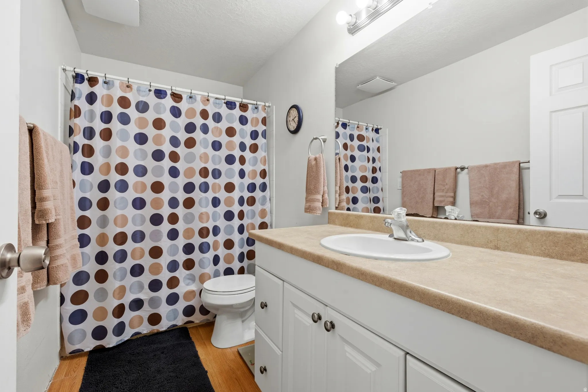 Bathroom featuring vanity, a shower with curtain, light wood finished floors, and a textured ceiling