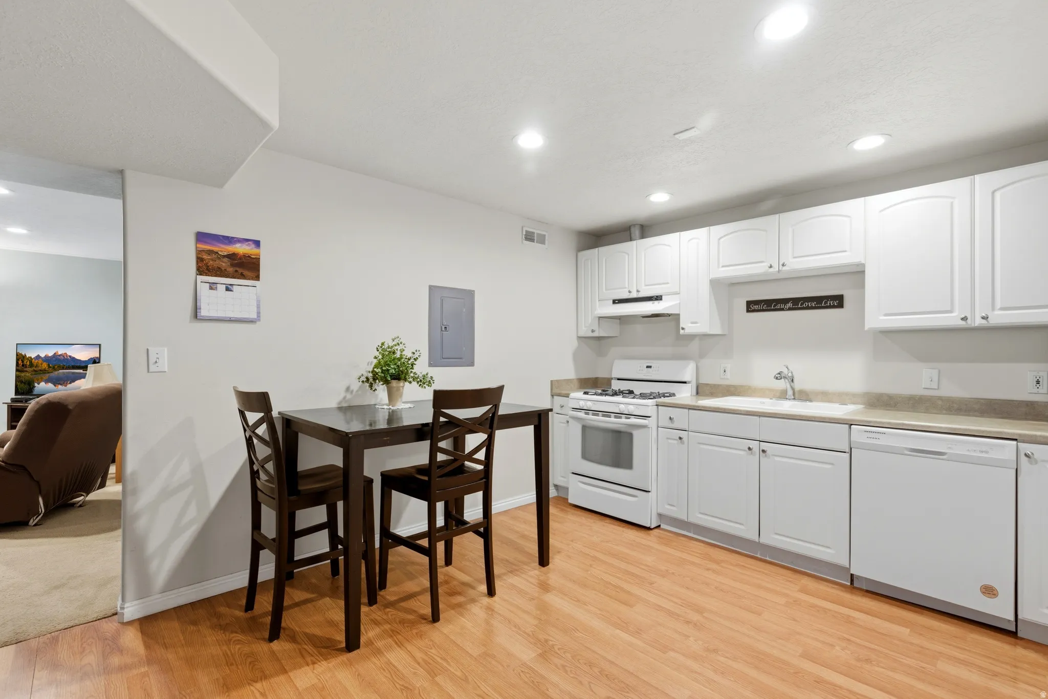 Kitchen with white cabinets, white appliances, recessed lighting, light countertops, and light wood-type flooring