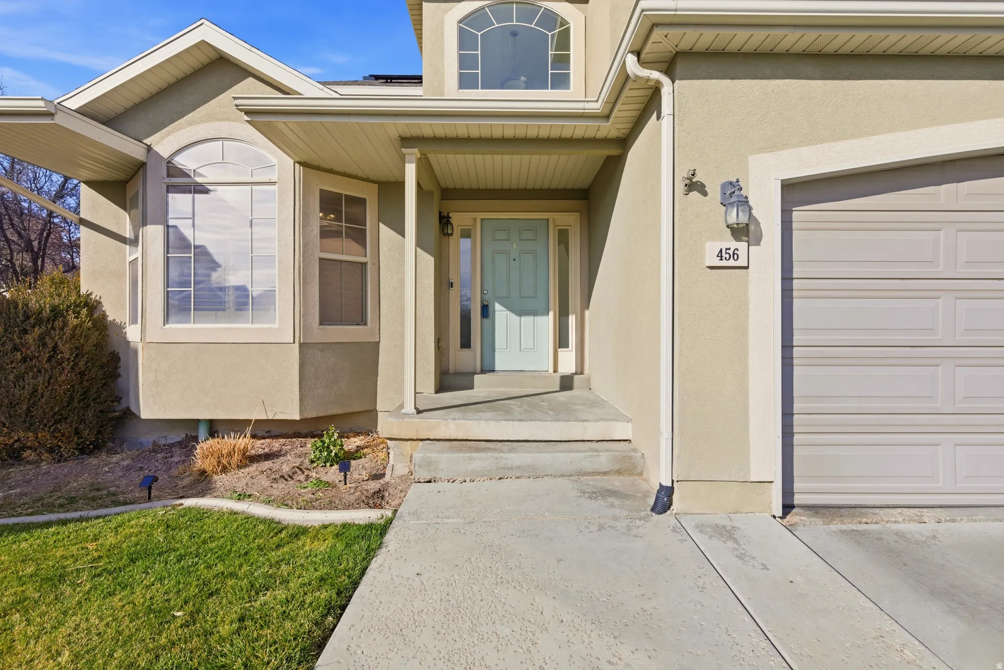 View of exterior entry featuring stucco siding, a garage, and covered porch