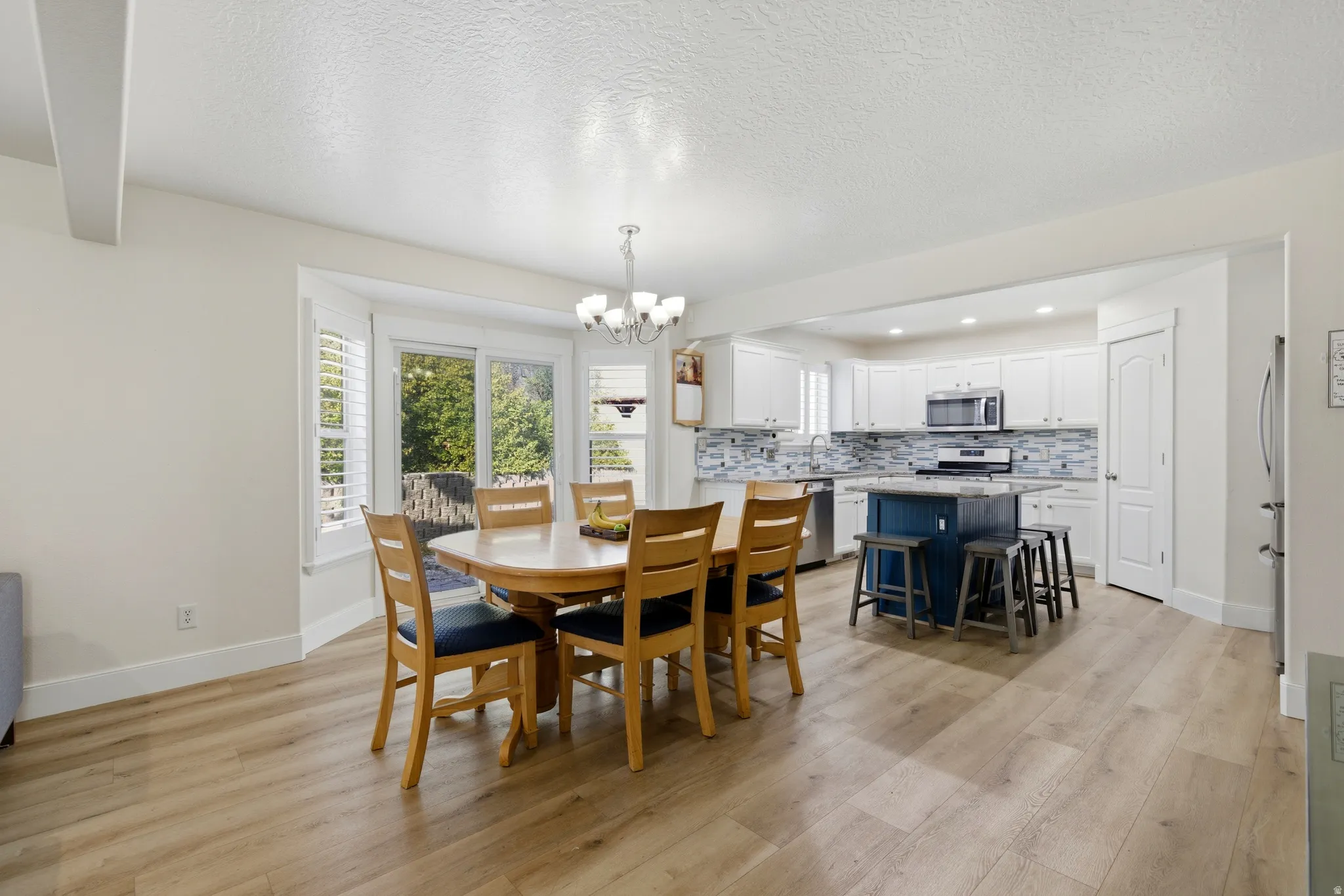 Dining space with a chandelier, light wood-type flooring, and a textured ceiling