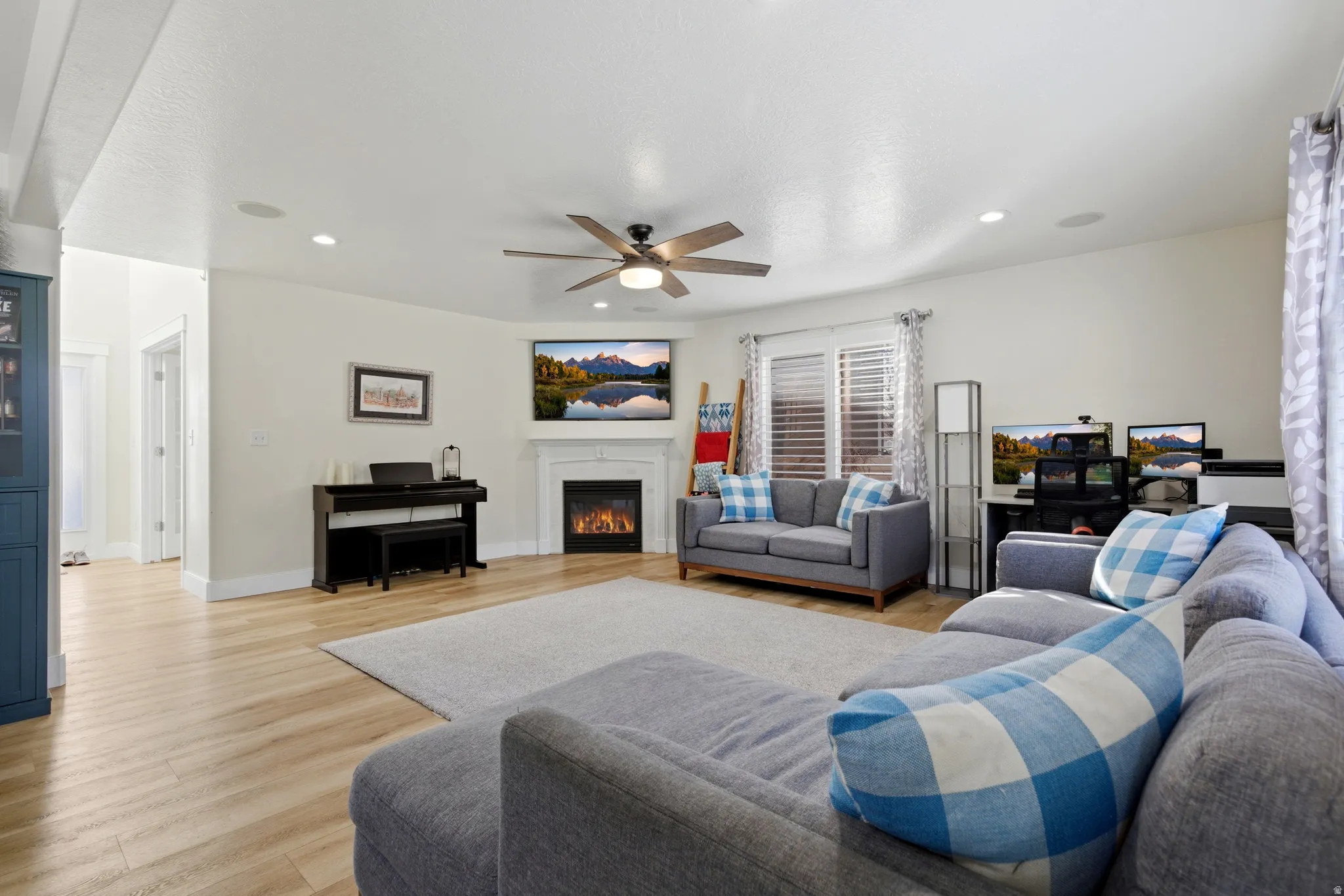 Living area featuring a glass covered fireplace, light wood-type flooring, ceiling fan, and recessed lighting