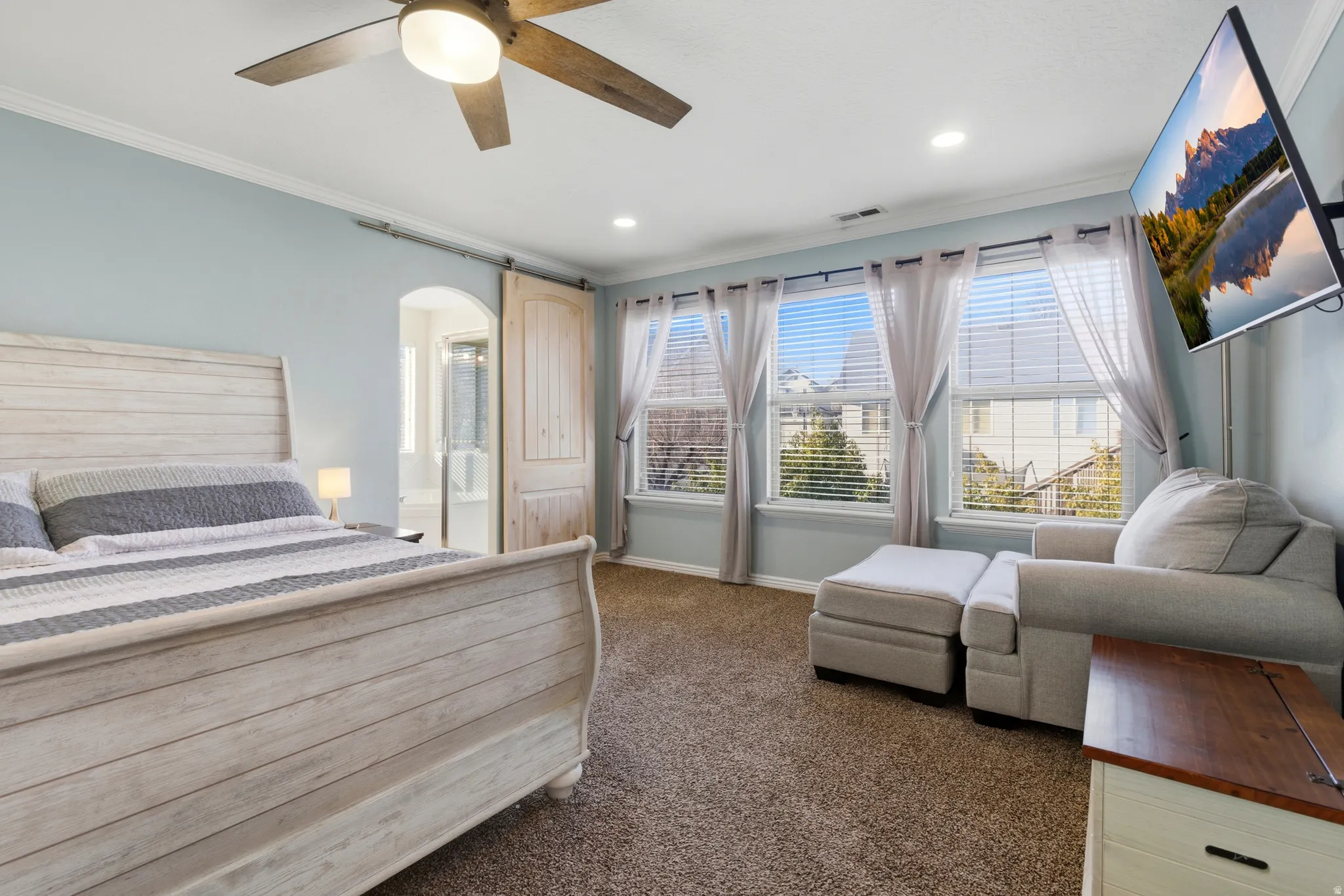 Bedroom with crown molding, dark colored carpet, a ceiling fan, arched walkways, and recessed lighting