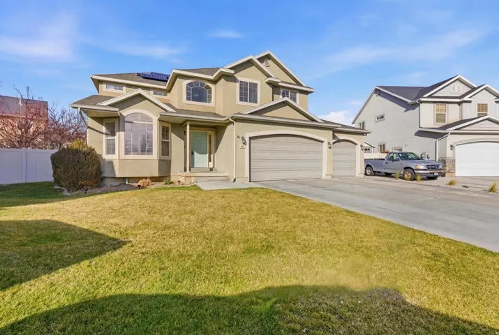 Traditional-style home with driveway, stucco siding, roof mounted solar panels, and a garage