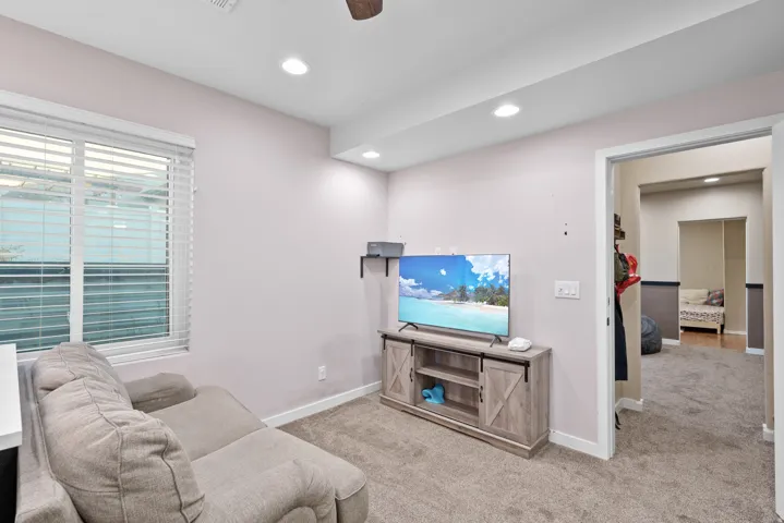 Living area with carpet flooring, a ceiling fan, and recessed lighting