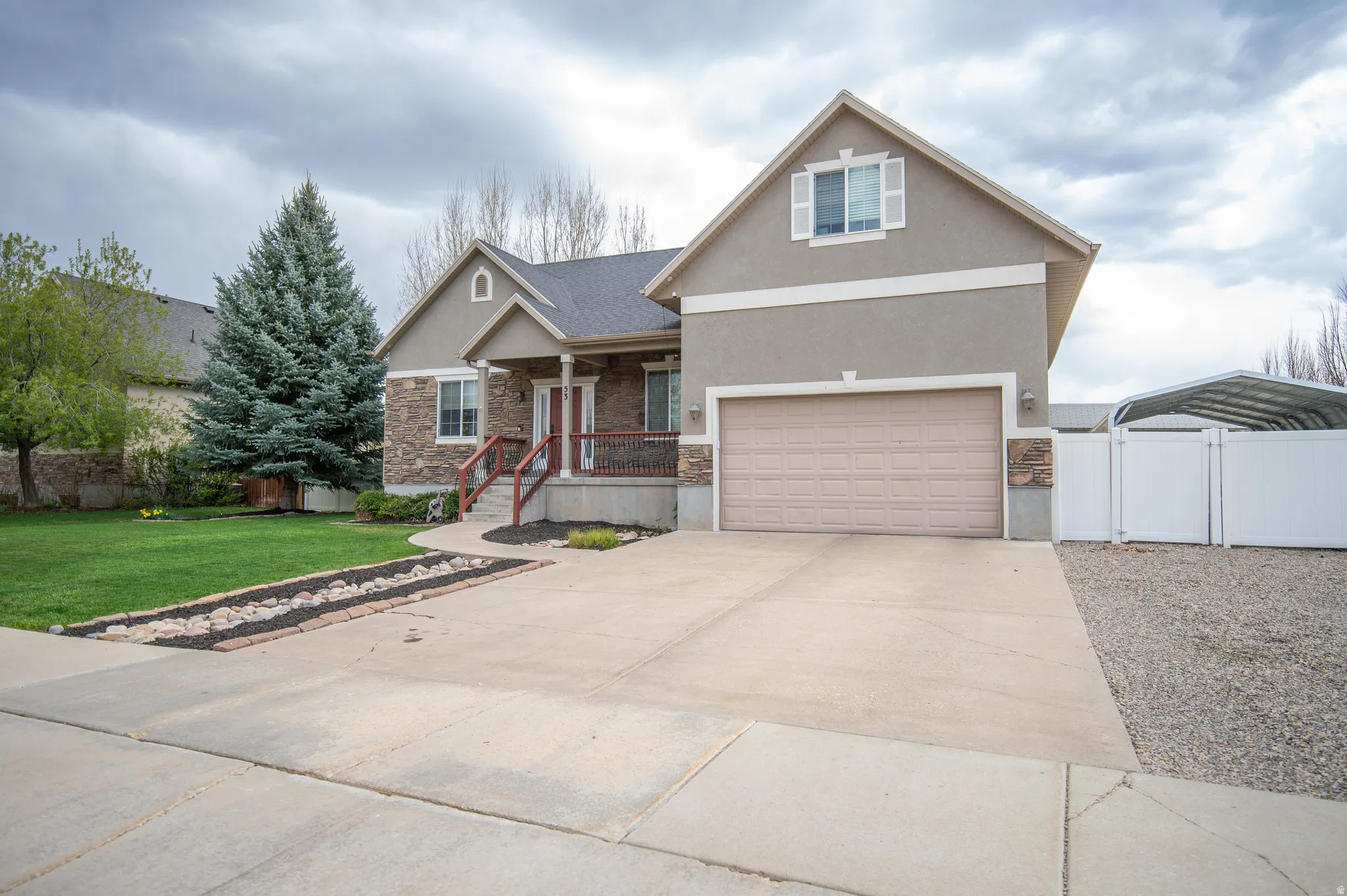 Craftsman-style house featuring a carport, a gate, a porch, driveway, and stucco siding