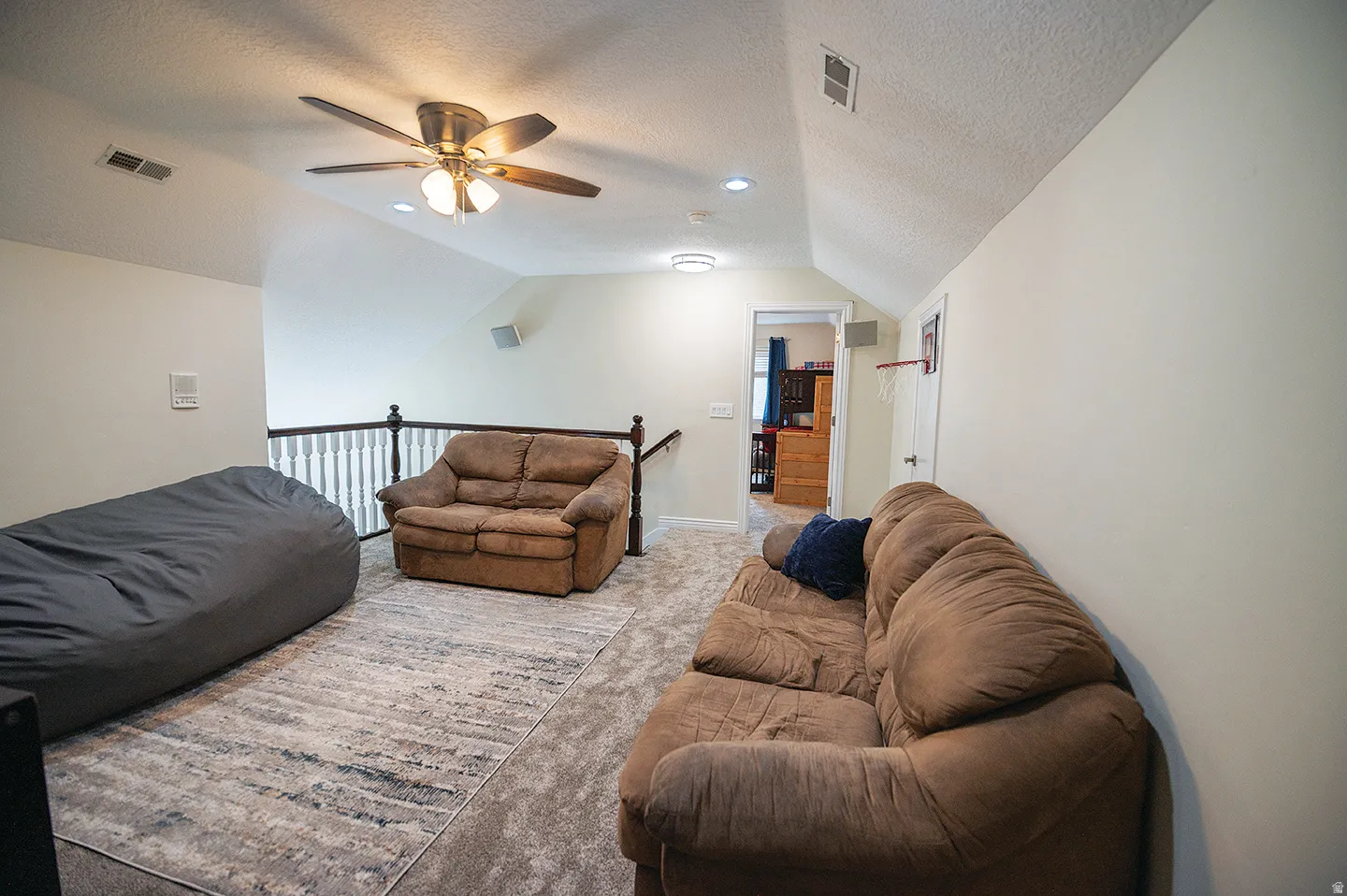Living room featuring carpet floors, a textured ceiling, ceiling fan, and vaulted ceiling