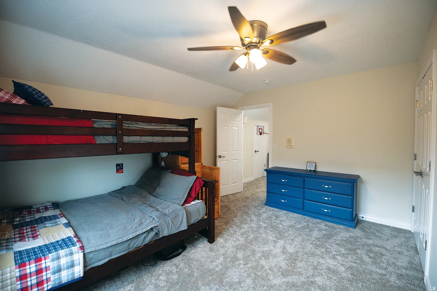 Carpeted bedroom featuring lofted ceiling and a ceiling fan