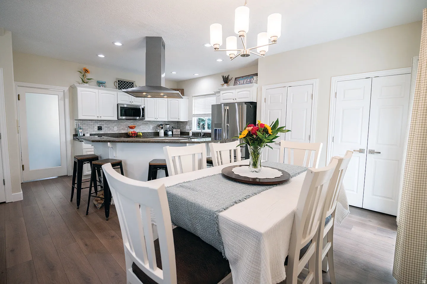 Dining space with dark wood finished floors, a chandelier, and recessed lighting
