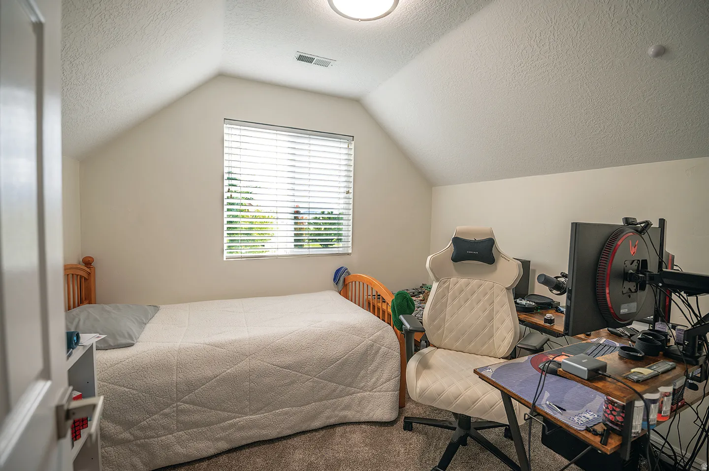 Bedroom with a textured ceiling, lofted ceiling, and carpet flooring