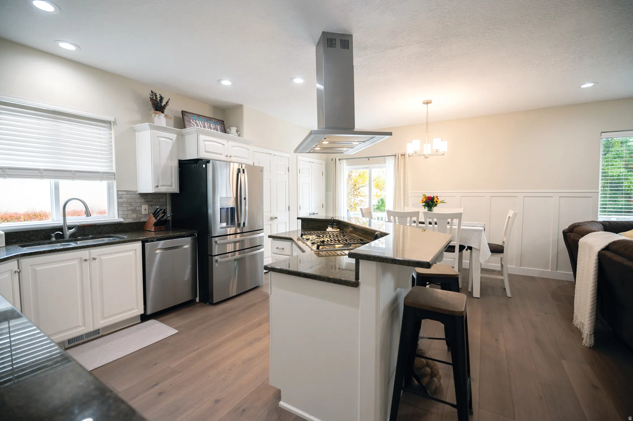 Kitchen featuring a kitchen island, a kitchen breakfast bar, white cabinetry, island range hood, and recessed lighting