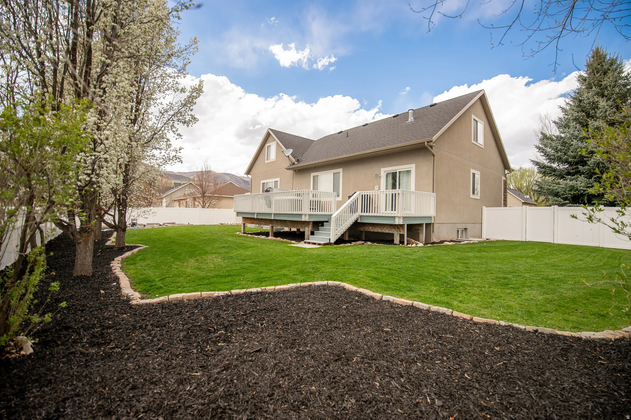 Back of property with a fenced backyard and a deck