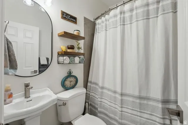 Full bathroom featuring curtained shower and toilet