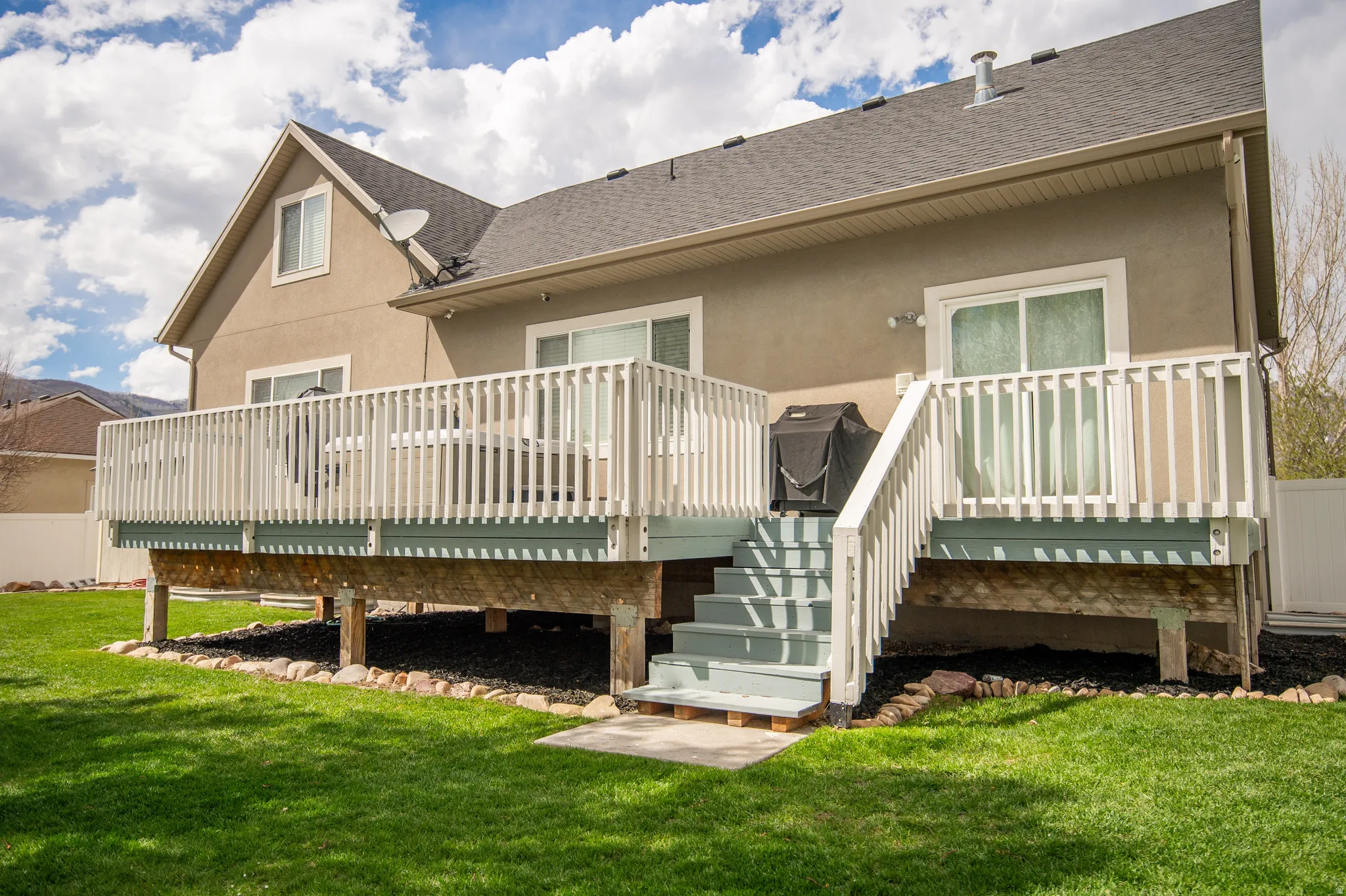 Back of house featuring stucco siding, a yard, a deck, and roof with shingles