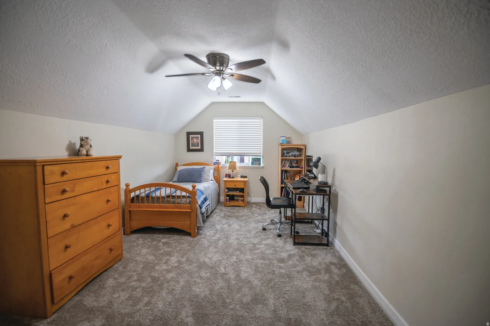 Bedroom featuring a textured ceiling, lofted ceiling, carpet, and ceiling fan