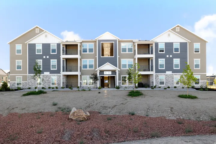Multi-story building featuring a blend of panel siding and stone facade, private balconies, and an inviting entry with a covered porch
