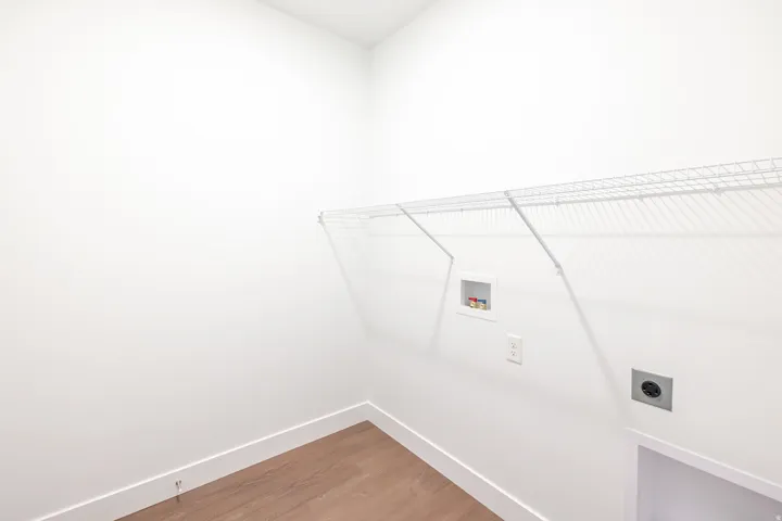 Dedicated utility space featuring a wire shelving unit, wood-finish flooring, and white baseboards