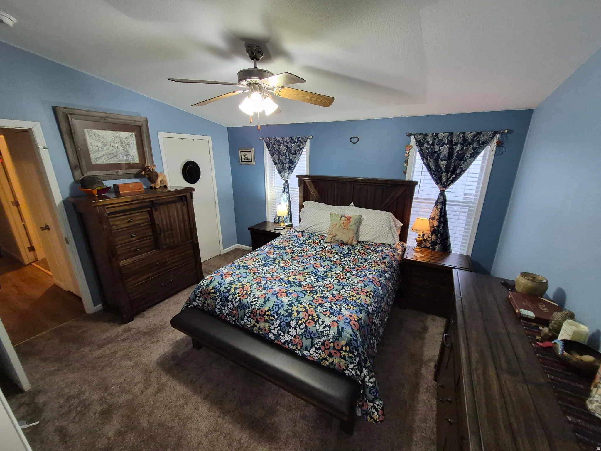 Carpeted bedroom featuring ceiling fan and lofted ceiling