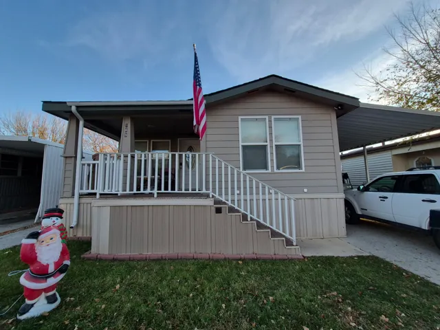 Rear view of property featuring a carport, stairway, a yard, and covered porch
