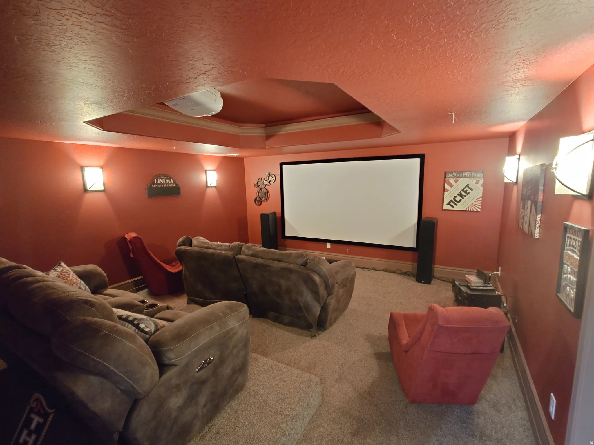 Home theater room with a tray ceiling, a textured ceiling, and carpet floors