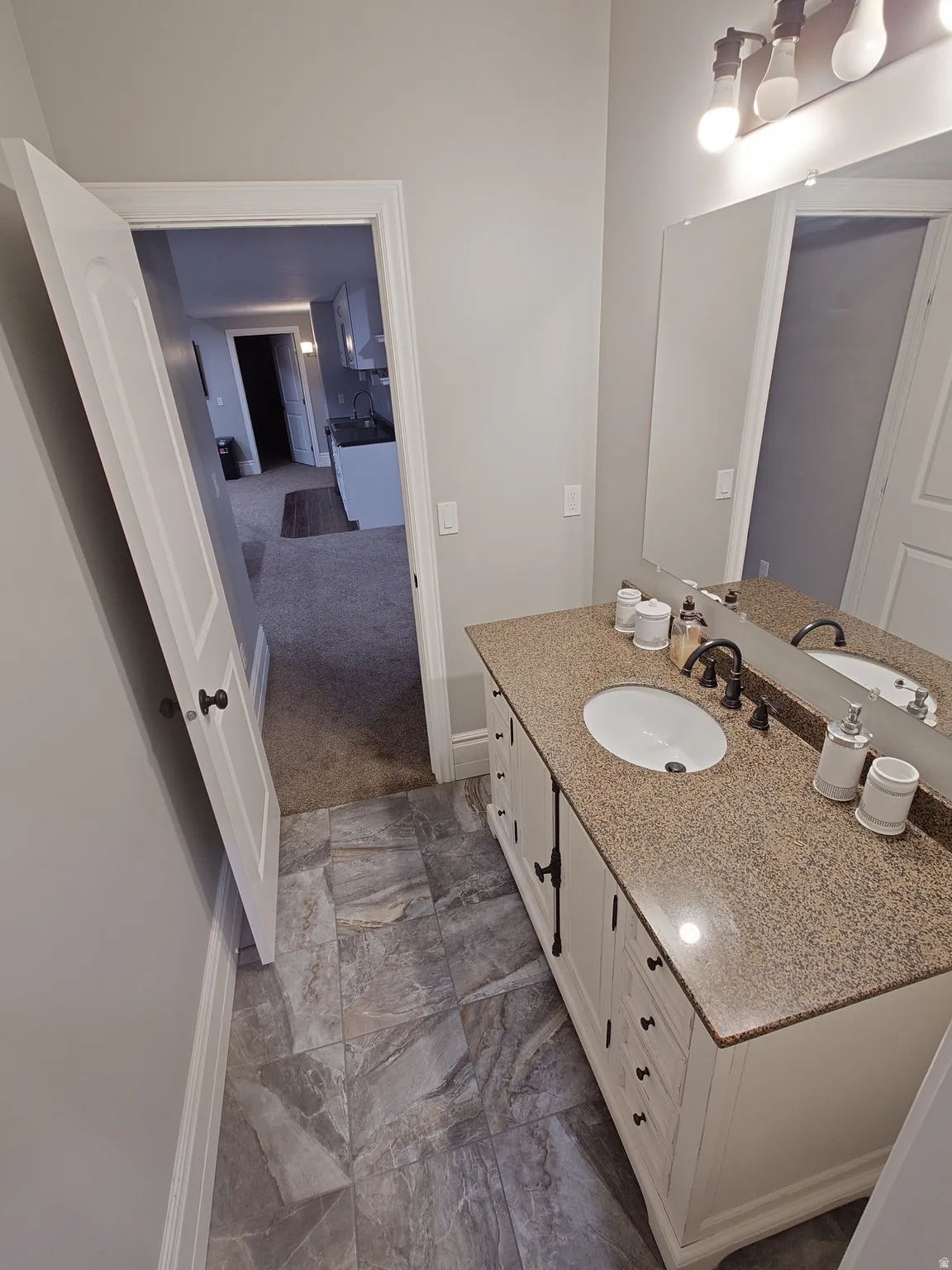 Bathroom with vanity and dark marble finish flooring