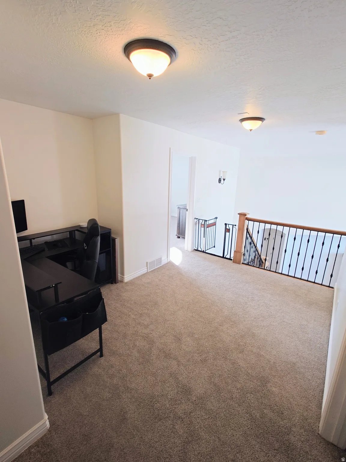 Carpeted home office with a textured ceiling
