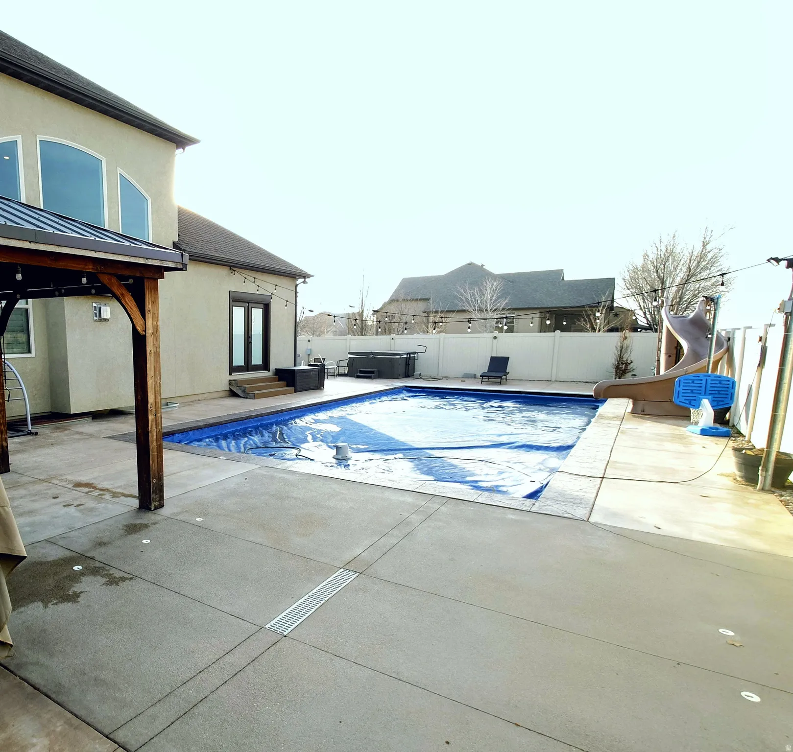 View of swimming pool featuring a patio, a water slide, a fenced backyard, a gazebo, and french doors