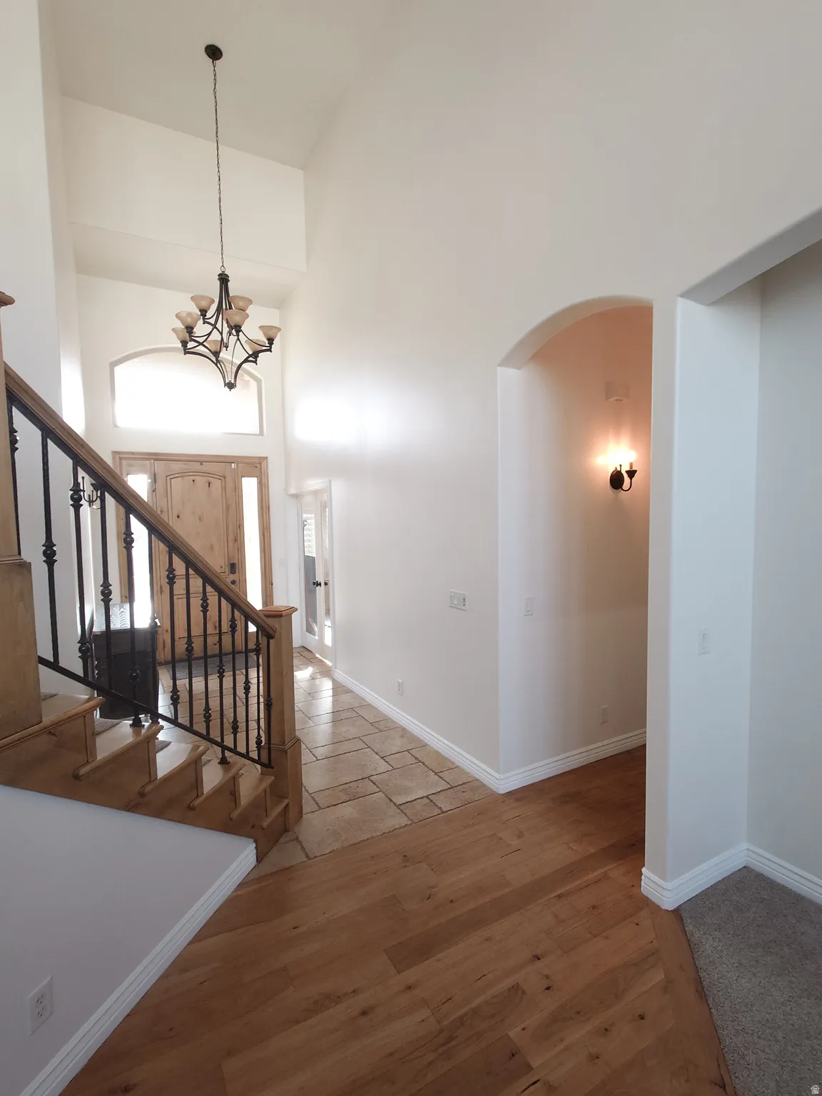 Stairs with arched walkways, a high ceiling, and wood finished floors