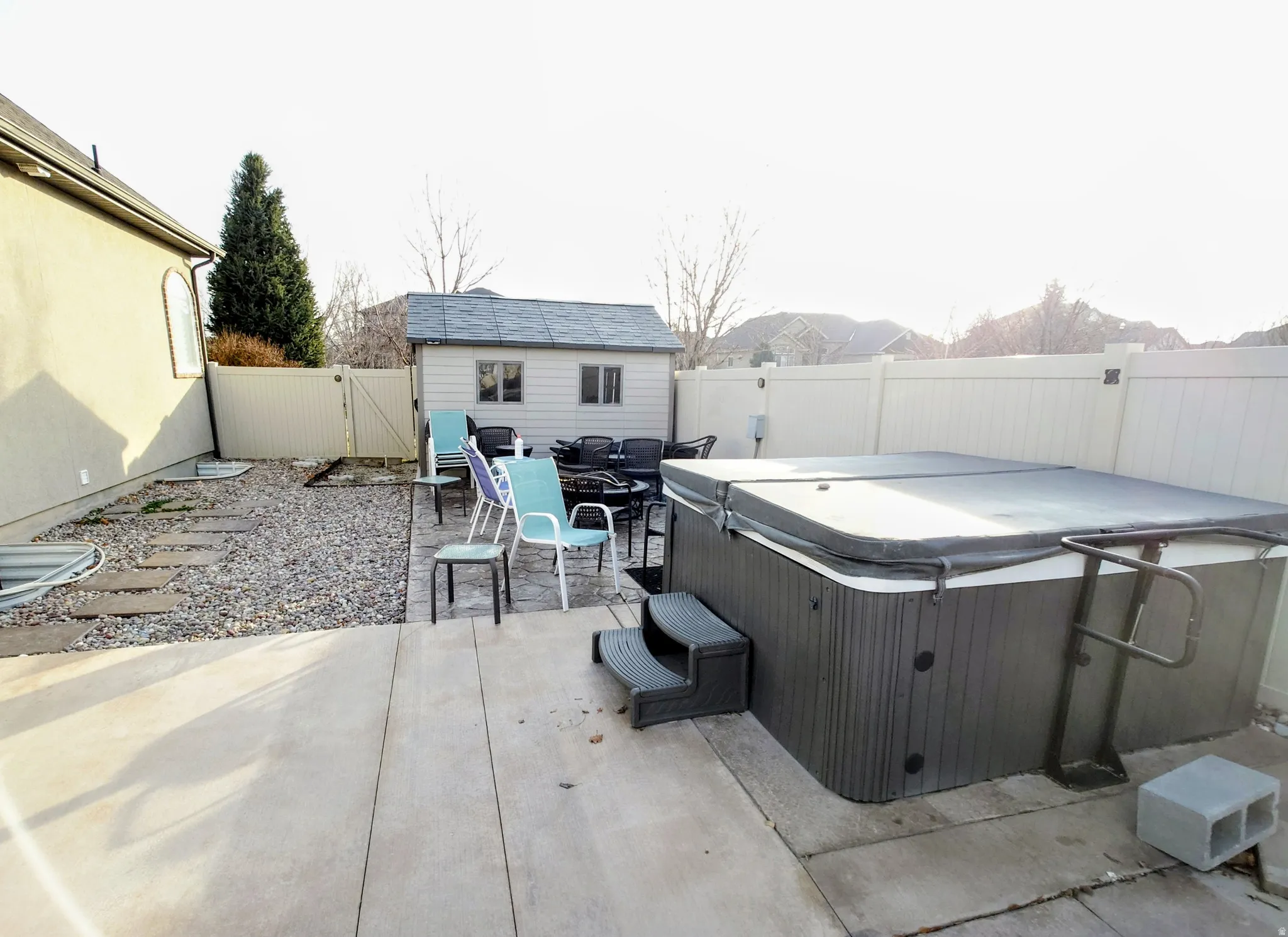 Fenced backyard featuring a patio area, a gate, an outbuilding, and outdoor dining area