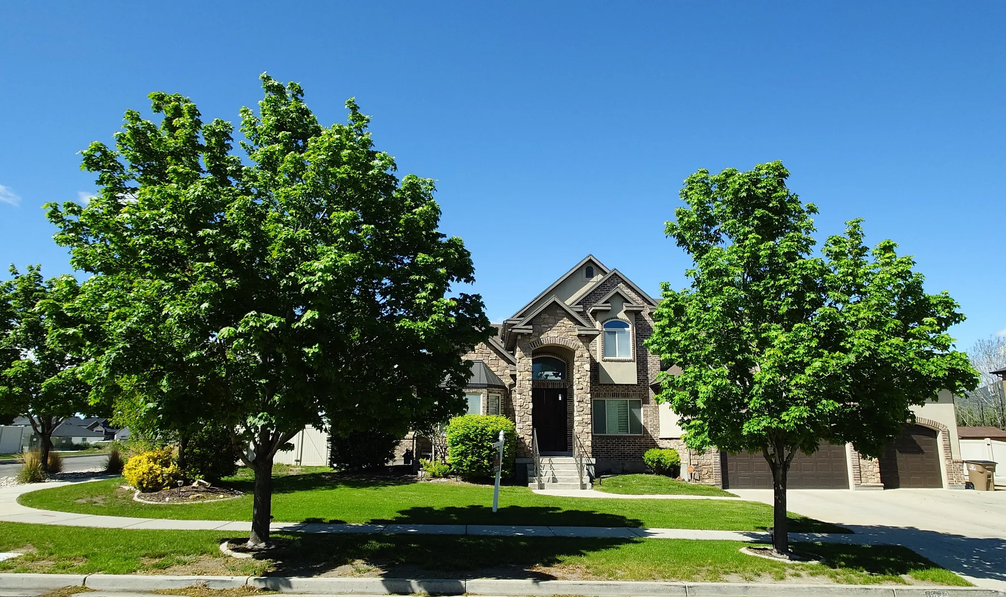 View of front of home featuring stone siding, a front lawn, driveway, and brick siding