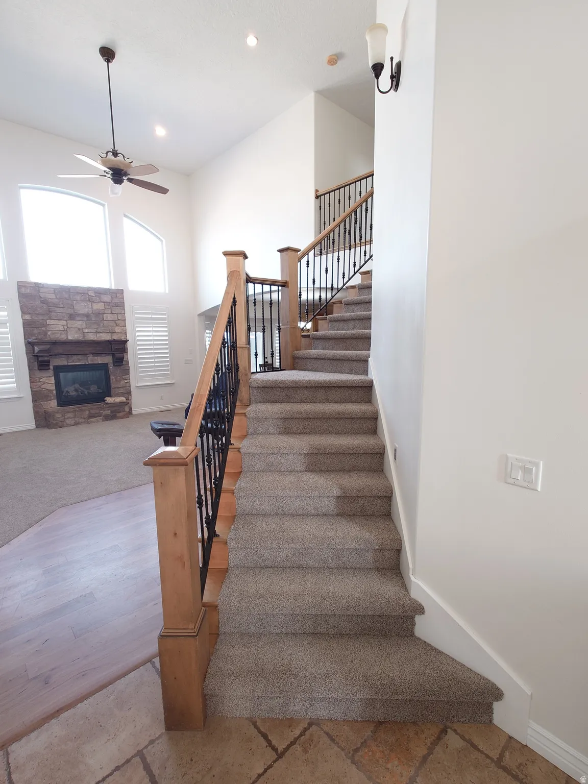 Stairs featuring ceiling fan, a stone fireplace, recessed lighting, and stone tile flooring