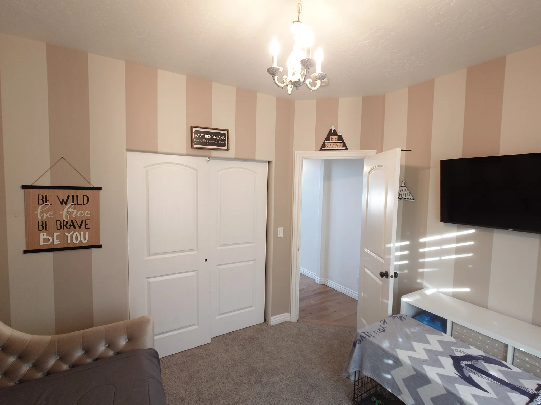 Bedroom with wallpapered walls, a chandelier, carpet, a closet, and a textured ceiling