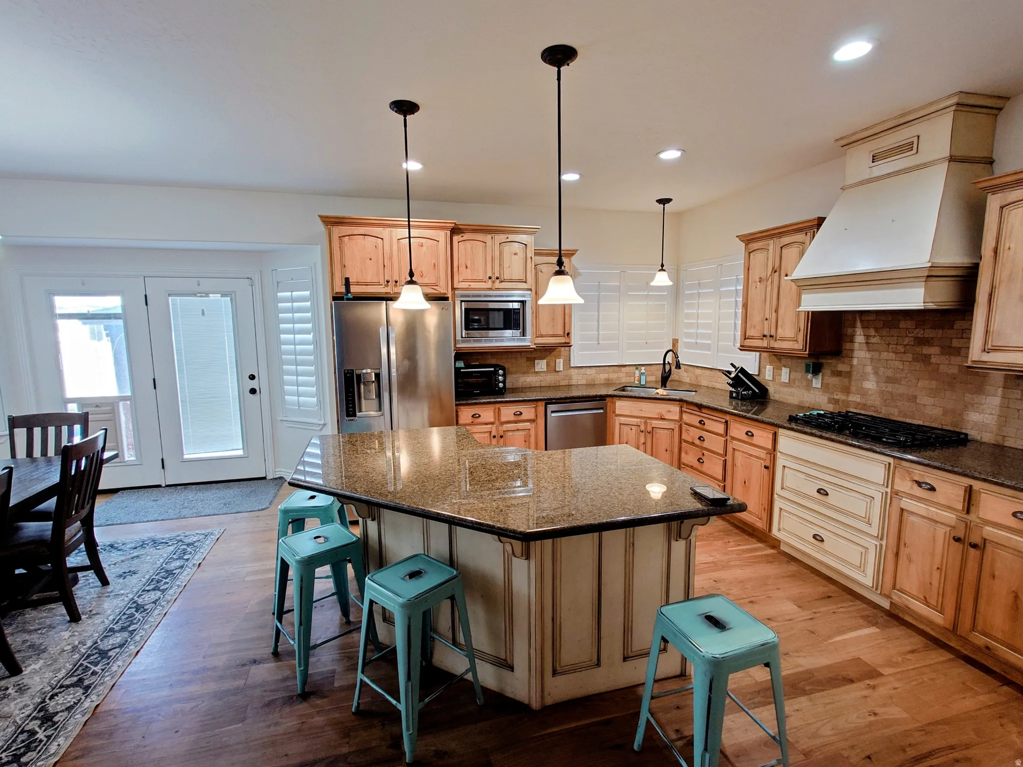 Kitchen with a breakfast bar, hanging light fixtures, backsplash, appliances with stainless steel finishes, and a center island
