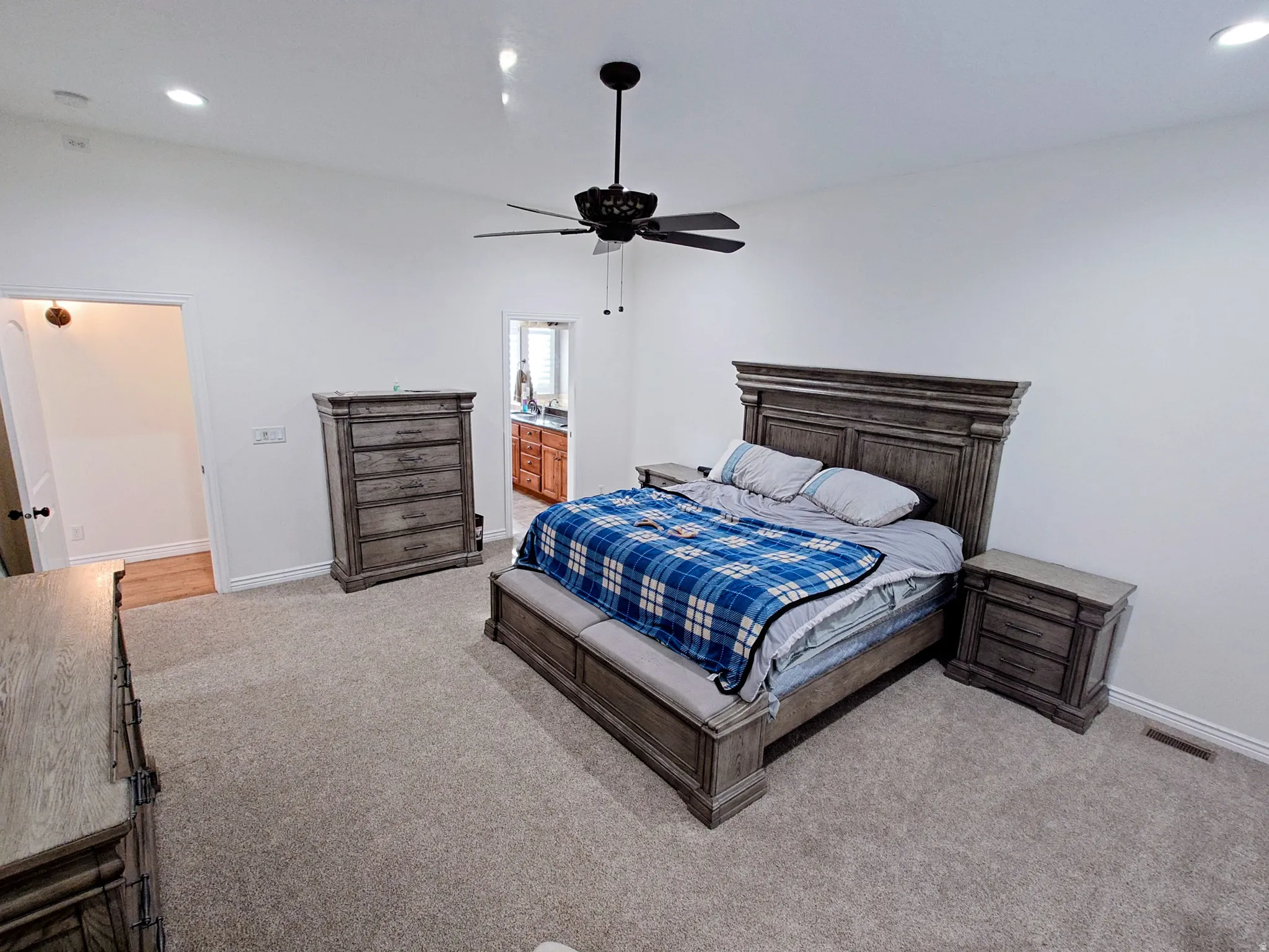 Bedroom with recessed lighting, a ceiling fan, light carpet, and connected bathroom