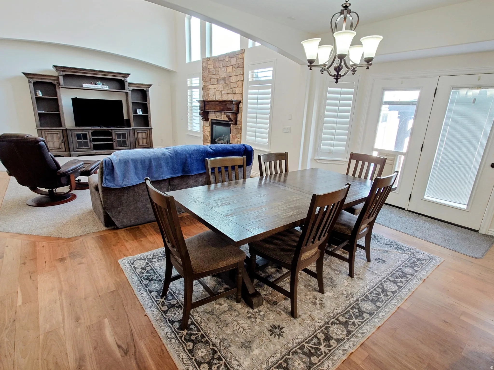 Dining area with a stone fireplace, light wood-type flooring, and a chandelier
