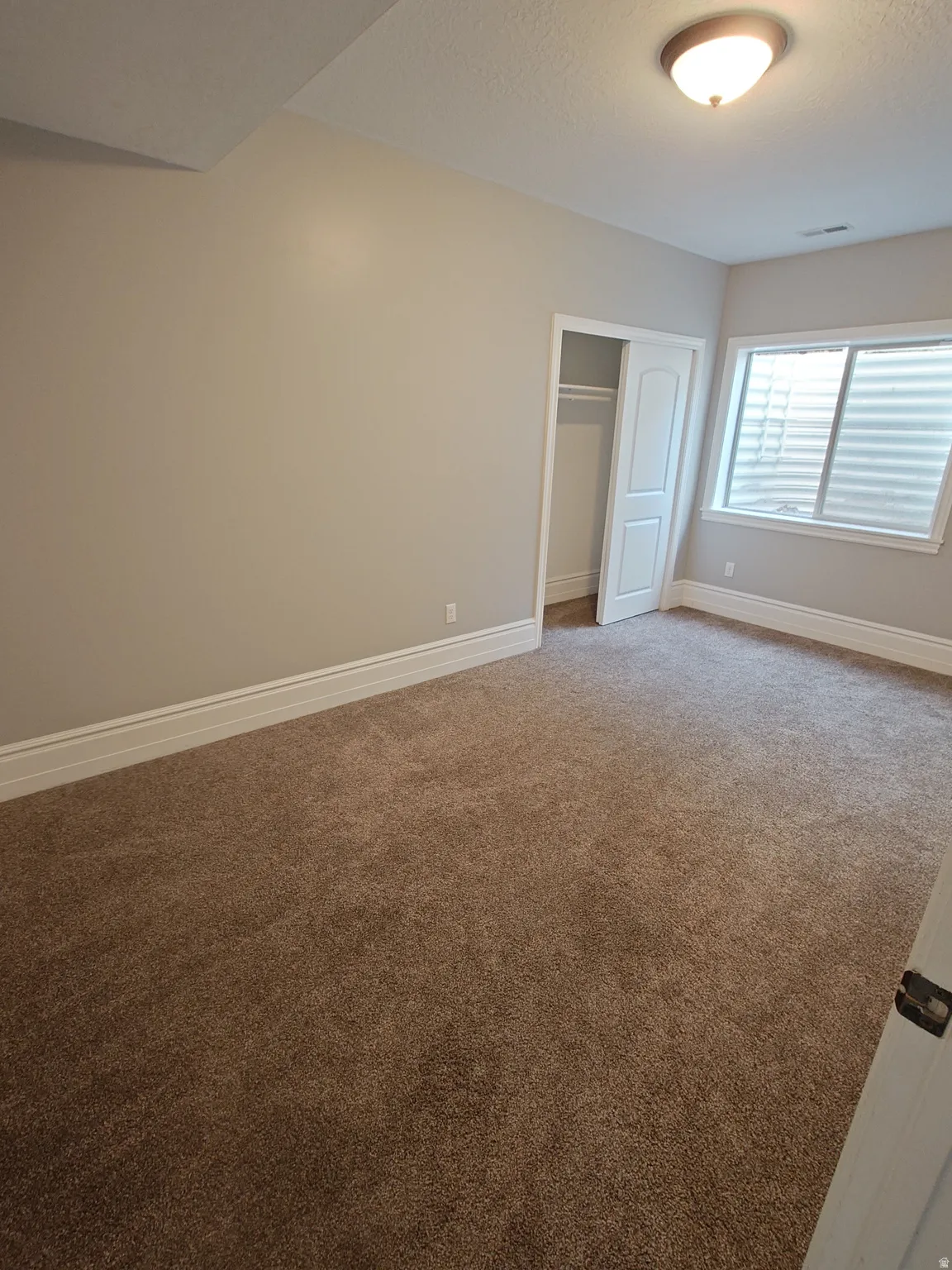 Unfurnished bedroom with a closet, light colored carpet, and a textured ceiling