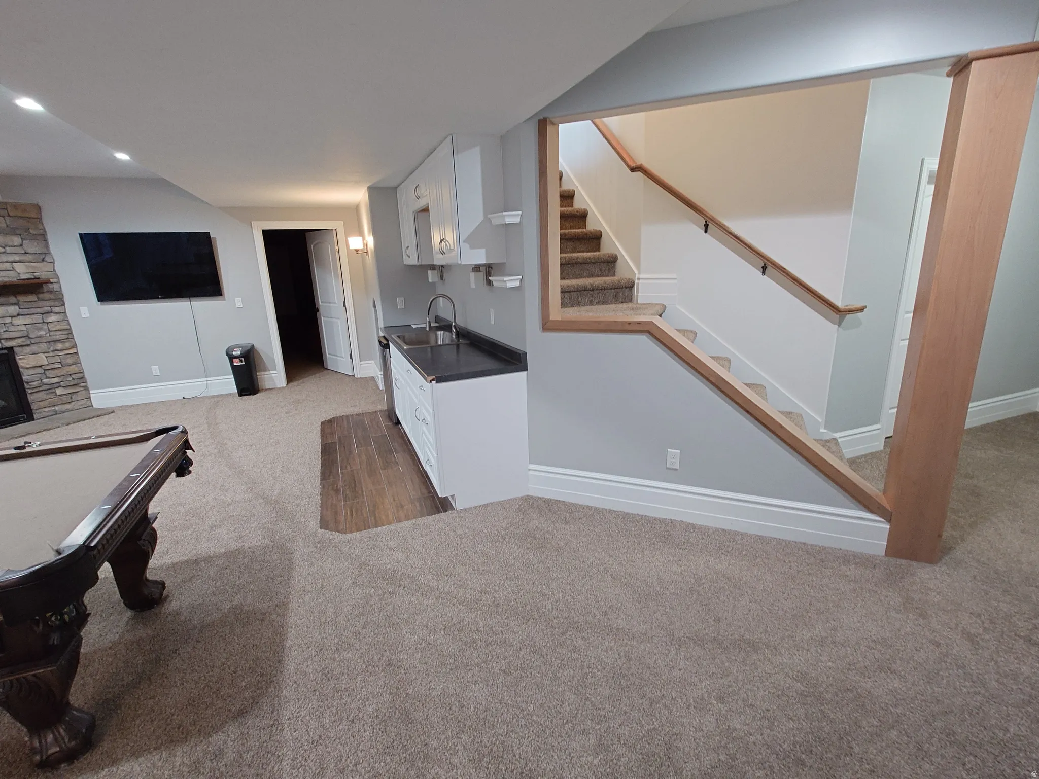 Bar featuring white cabinetry, dark countertops, pool table, light colored carpet, and stairway