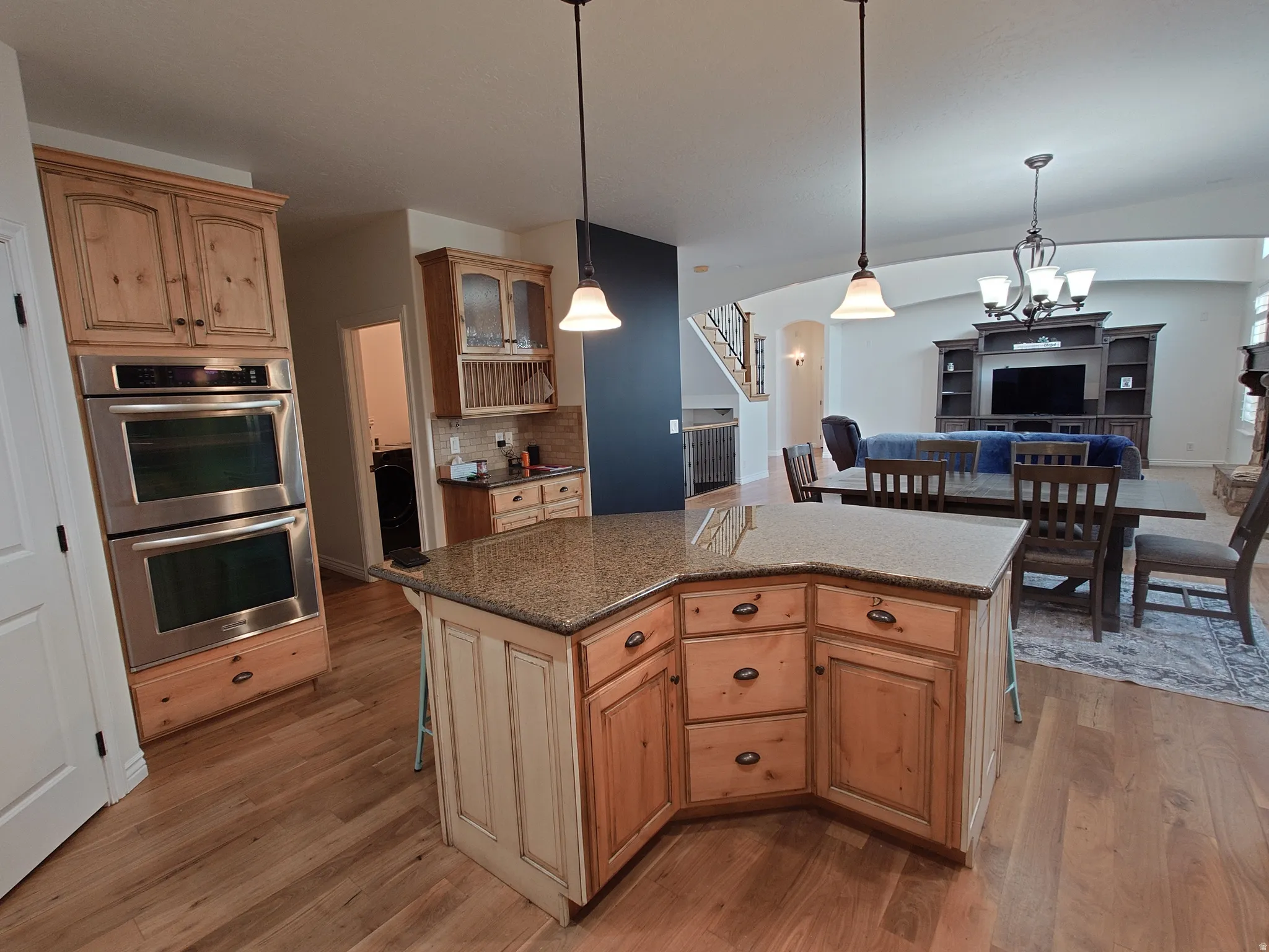Kitchen featuring stainless steel double oven, a kitchen bar, hanging light fixtures, and backsplash